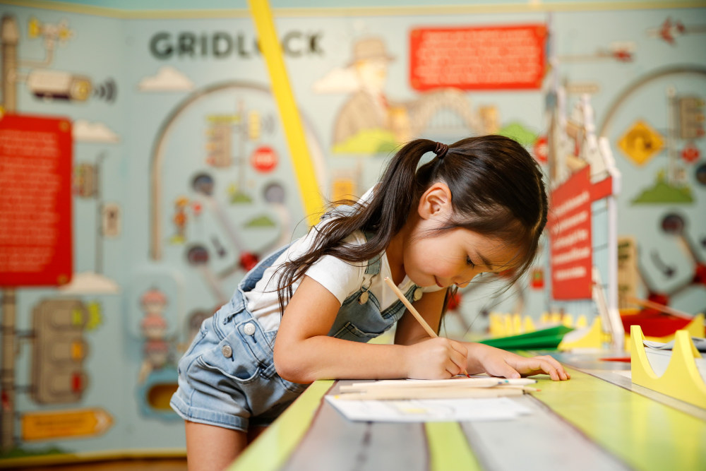 A young girl engrossed in an activity as part of the On the Move exhibition held at the Museum of Sydney