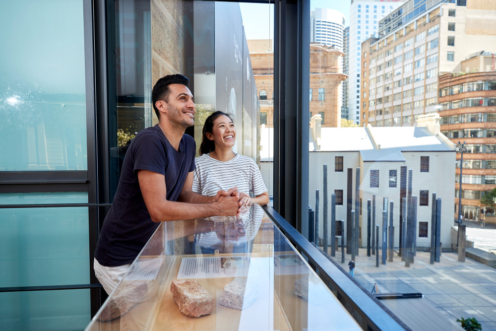 A couple look out onto the Museum of Sydney forecourt from the Sydney Visionaries gallery on level 2