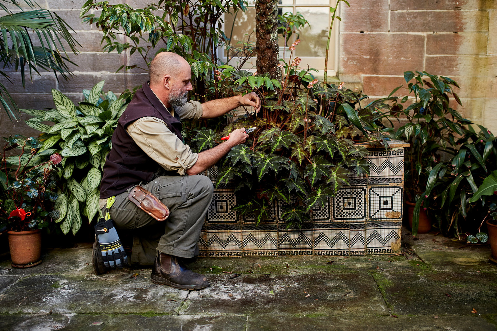 Man tending potted plants on stand.