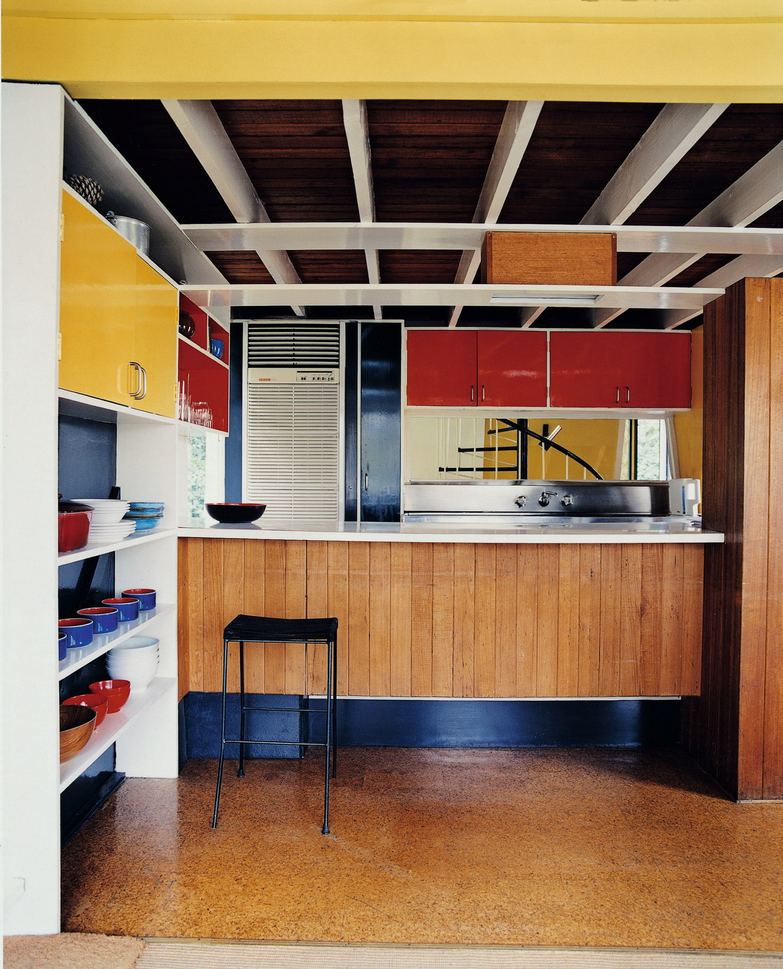 The kitchen of the Butterfly house featuring a bold colour palette for cupboard doors and the inside of the shelving
