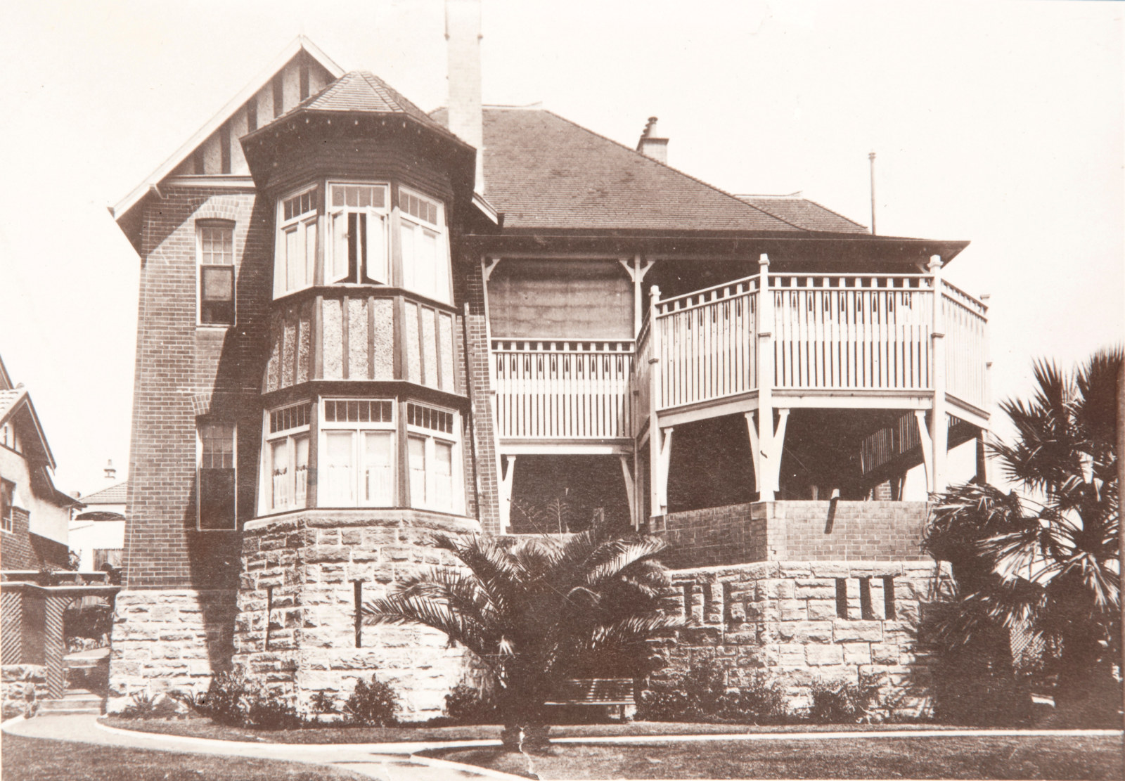 Black and white photo of two storey sandstone base house with verandahs.