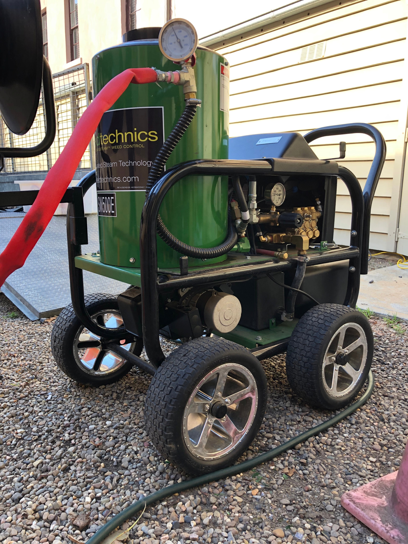the steam weeding machine is green and black and has a little chimney sticking out the top.