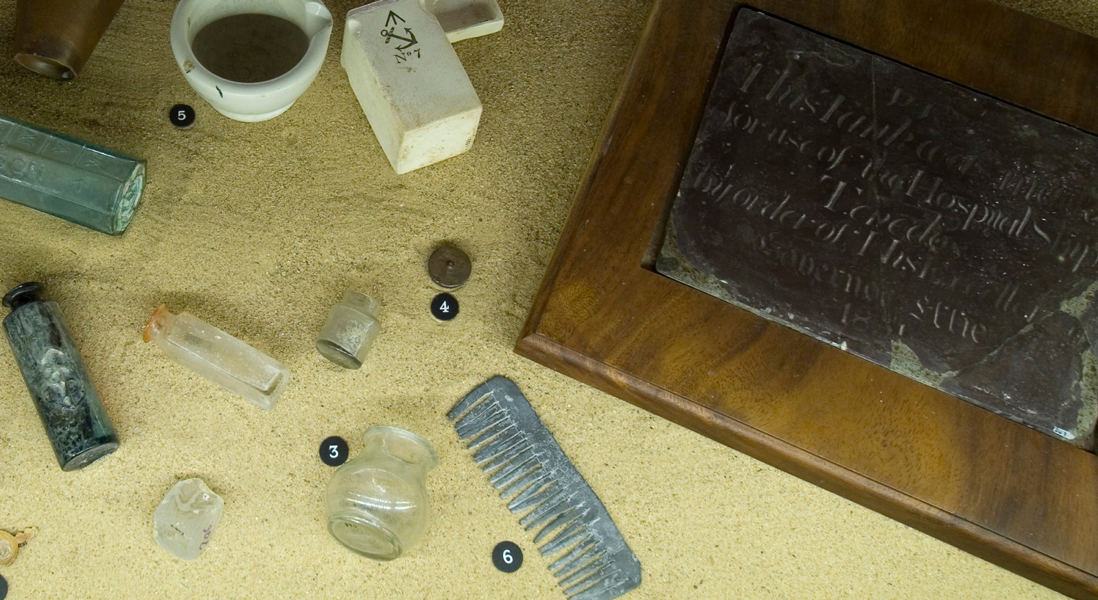 View of exhibition installation with ceramic and glass artefacts and plaque