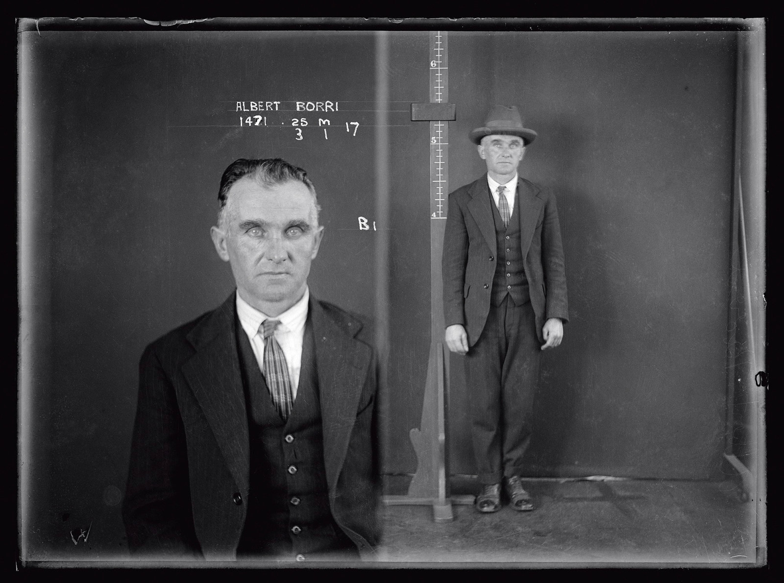 Dual mugshot in black and white; man seated and then man standing, with hat on.