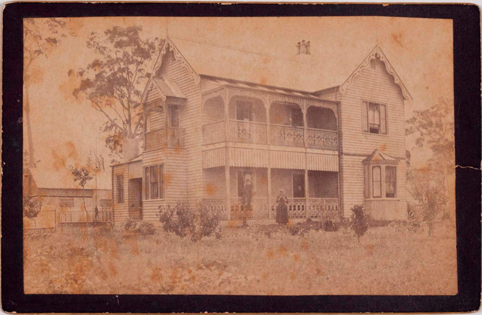 Photograph of exterior of house with three figures visible.