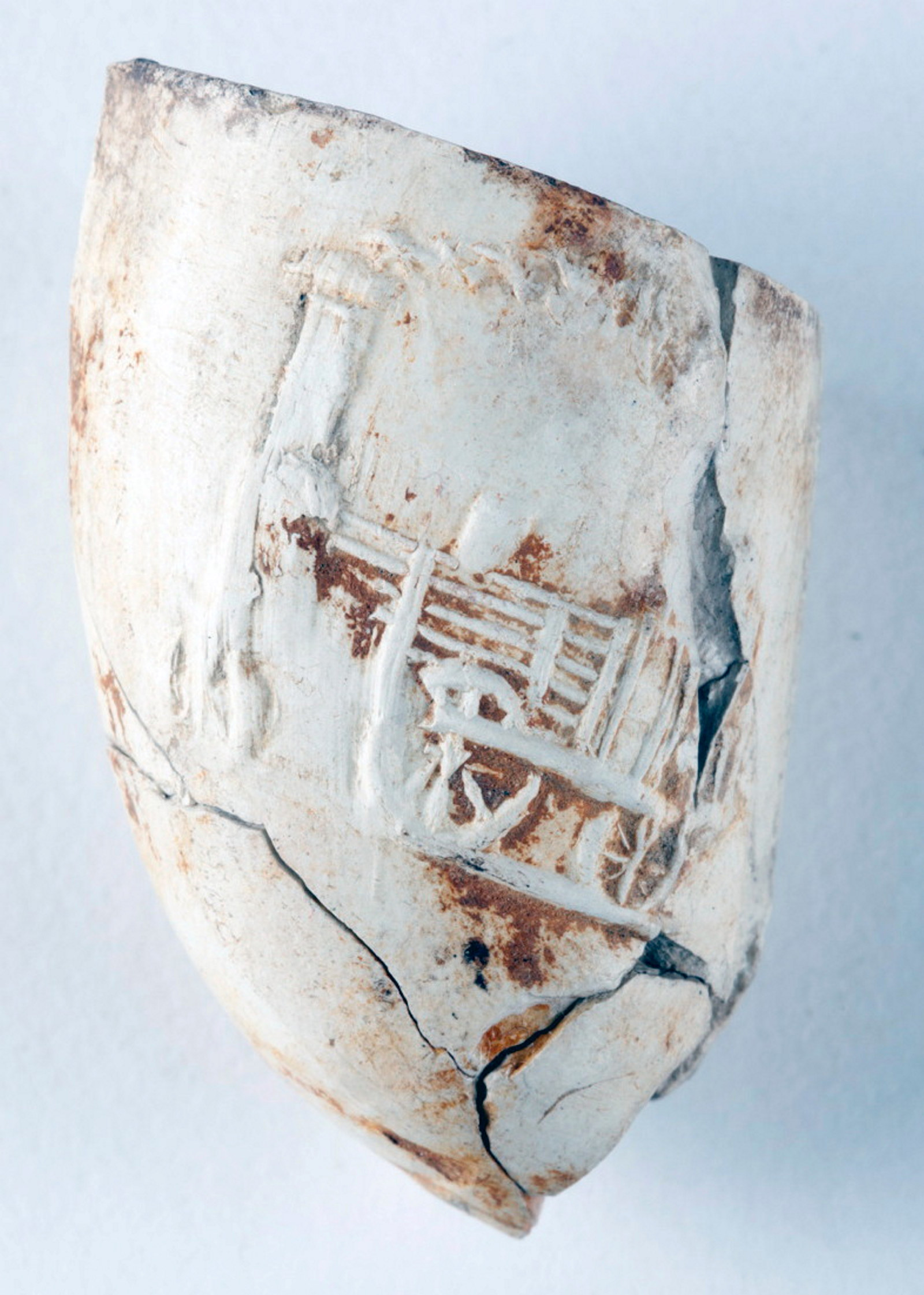 Close up of carved locomotive on white clay pipe bowl.