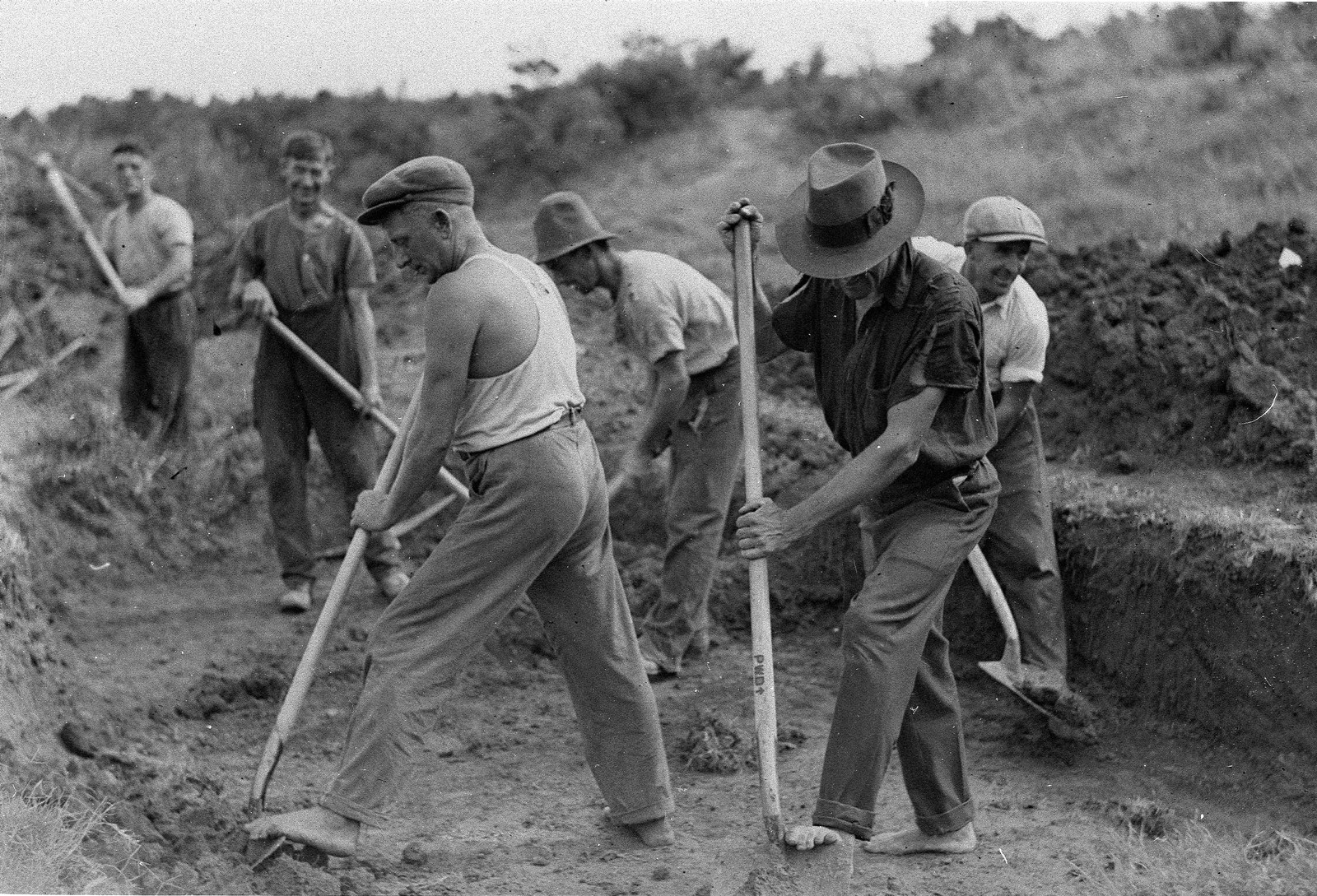 Black and white photo of men with digging equipment working outdoors.
