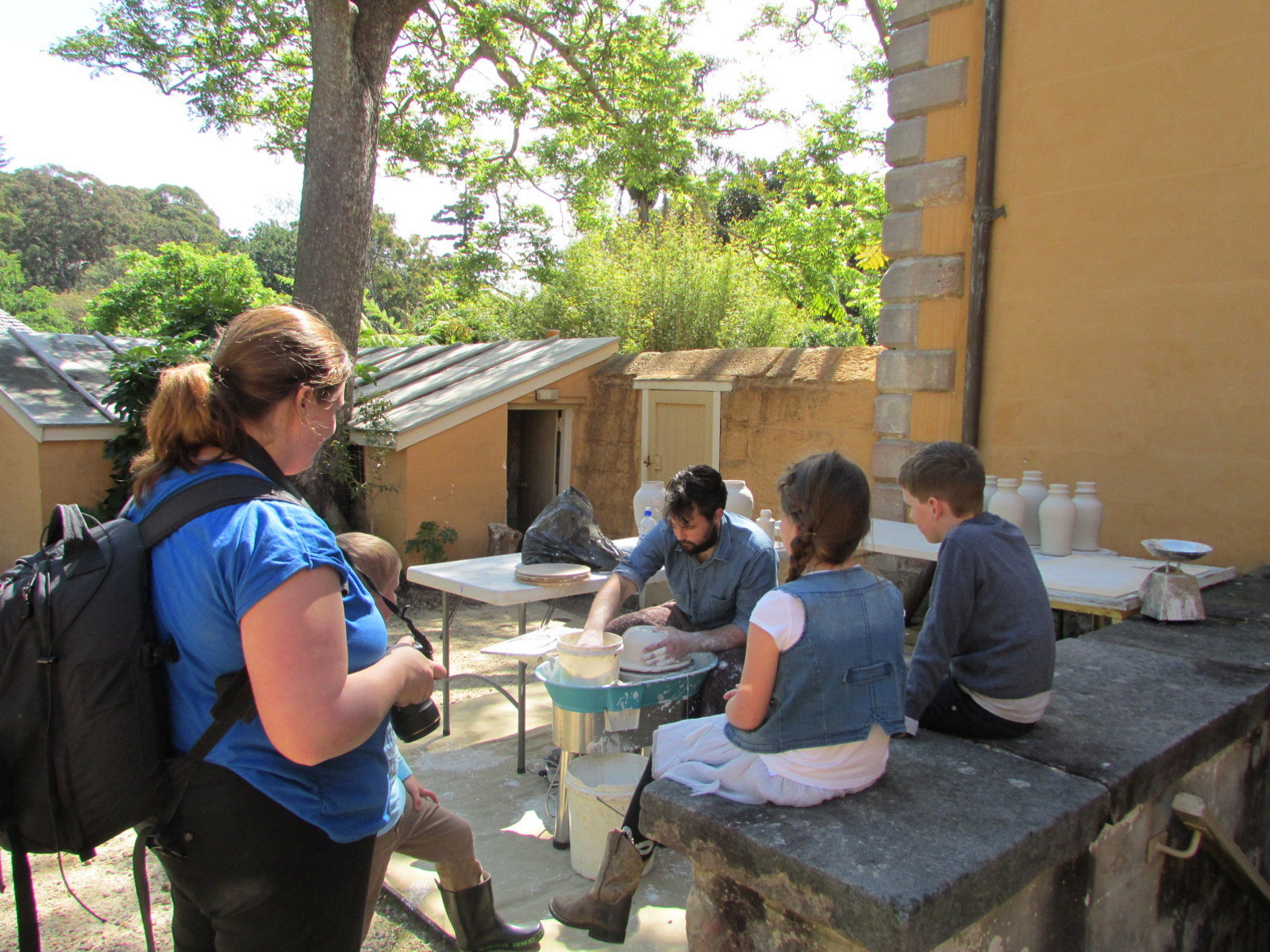 Artist in residence at work on the potters wheel in the stone walled courtyard of vaucluse house