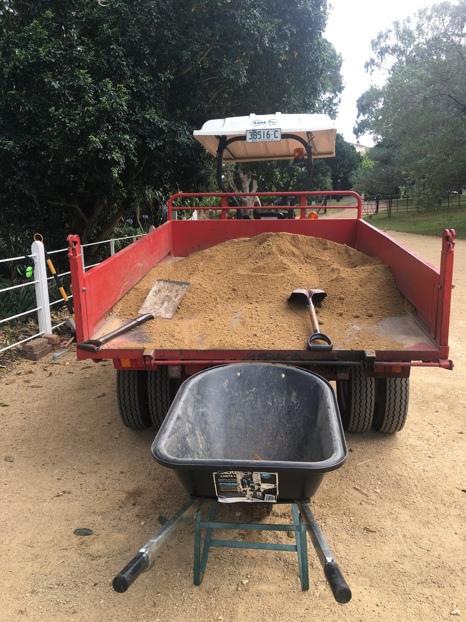 An empty wheelbarrow sits waiting to be filled with gravel from the tractor