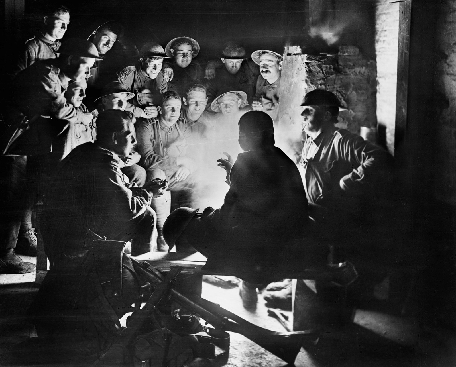 Members of the 1st Australian Light Trench Mortar Battery, 1st Australian Division, listening to ‘the latest’ from one of their comrades around a fire in a dugout billet at Ypres, 1917