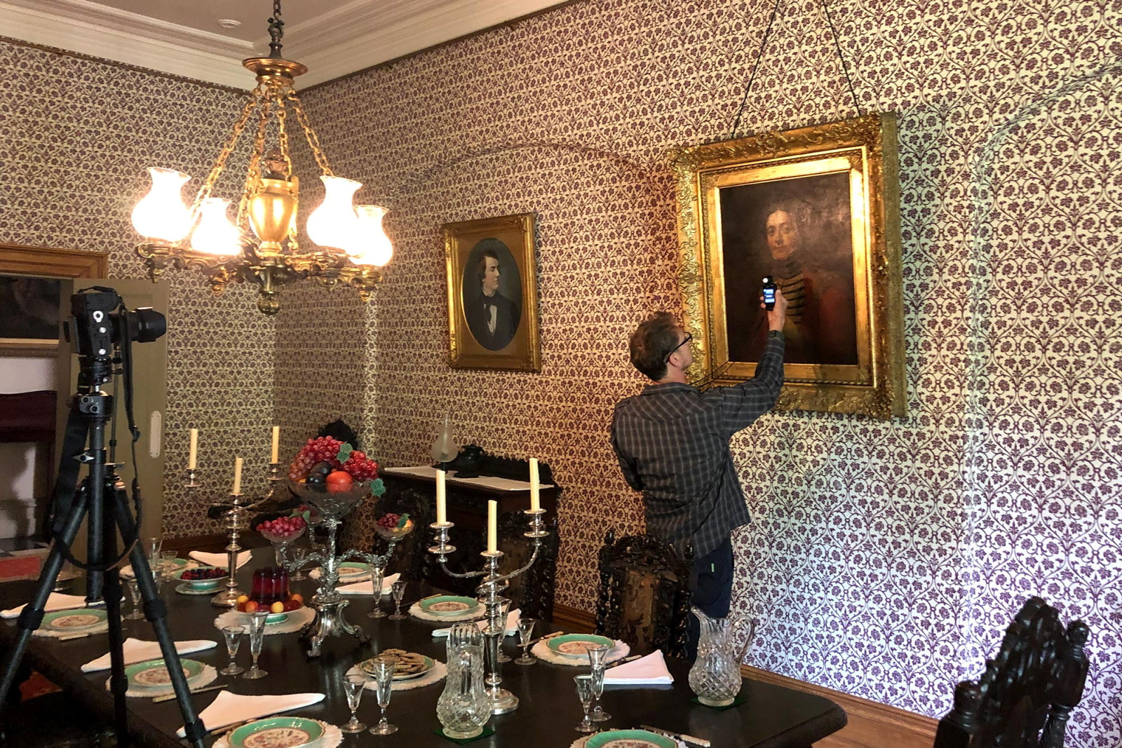 Man takes a light meter reading in preparation for photographing a painting in the Vaucluse House dining room.
