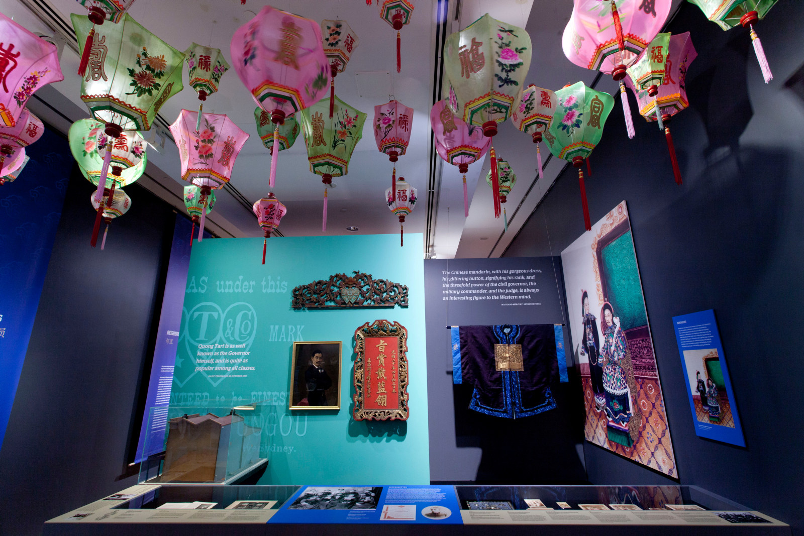 Exhibition view featuring objects in showcases and colourful Shanghai lanterns overhead