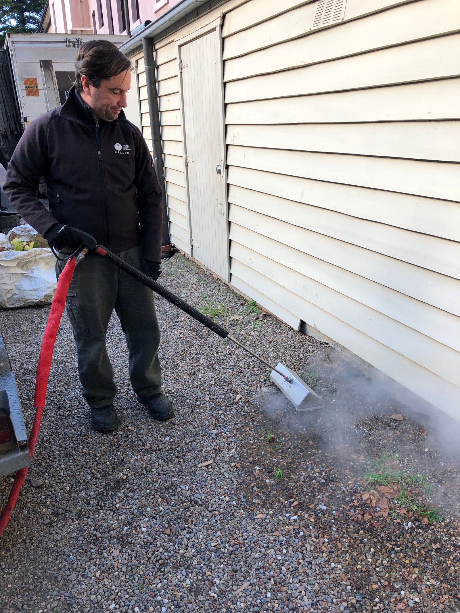 A SLM staff member uses a steam weeding machine to kill weeds alongside the driveway at the mint.