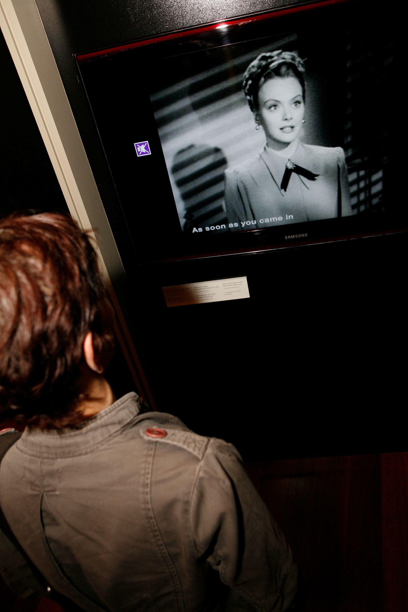 A visitor watches footage in the Femme Fatale exhibition at the Justice & Police Museum