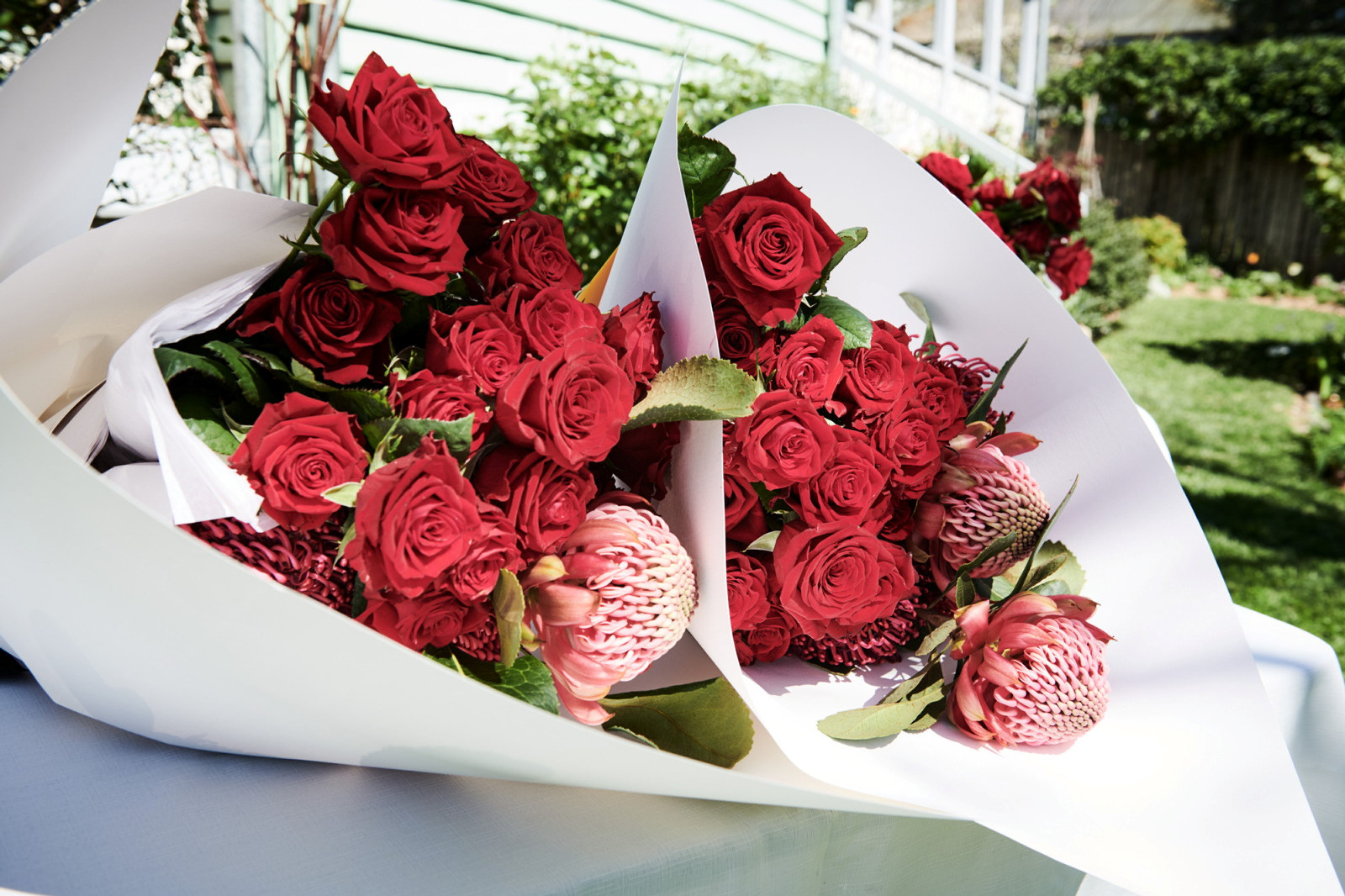 Two bouquets of red flowers and roses wrapped in white paper