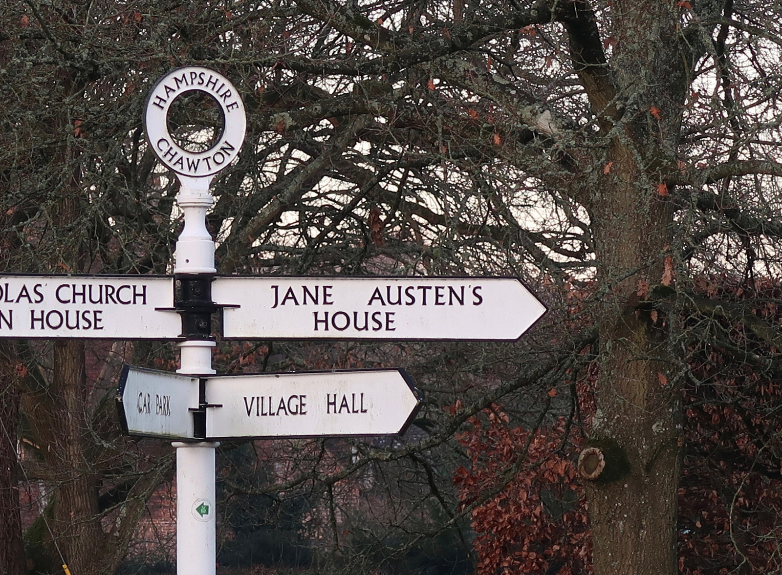 White signpost with several signs pointing in different directions.