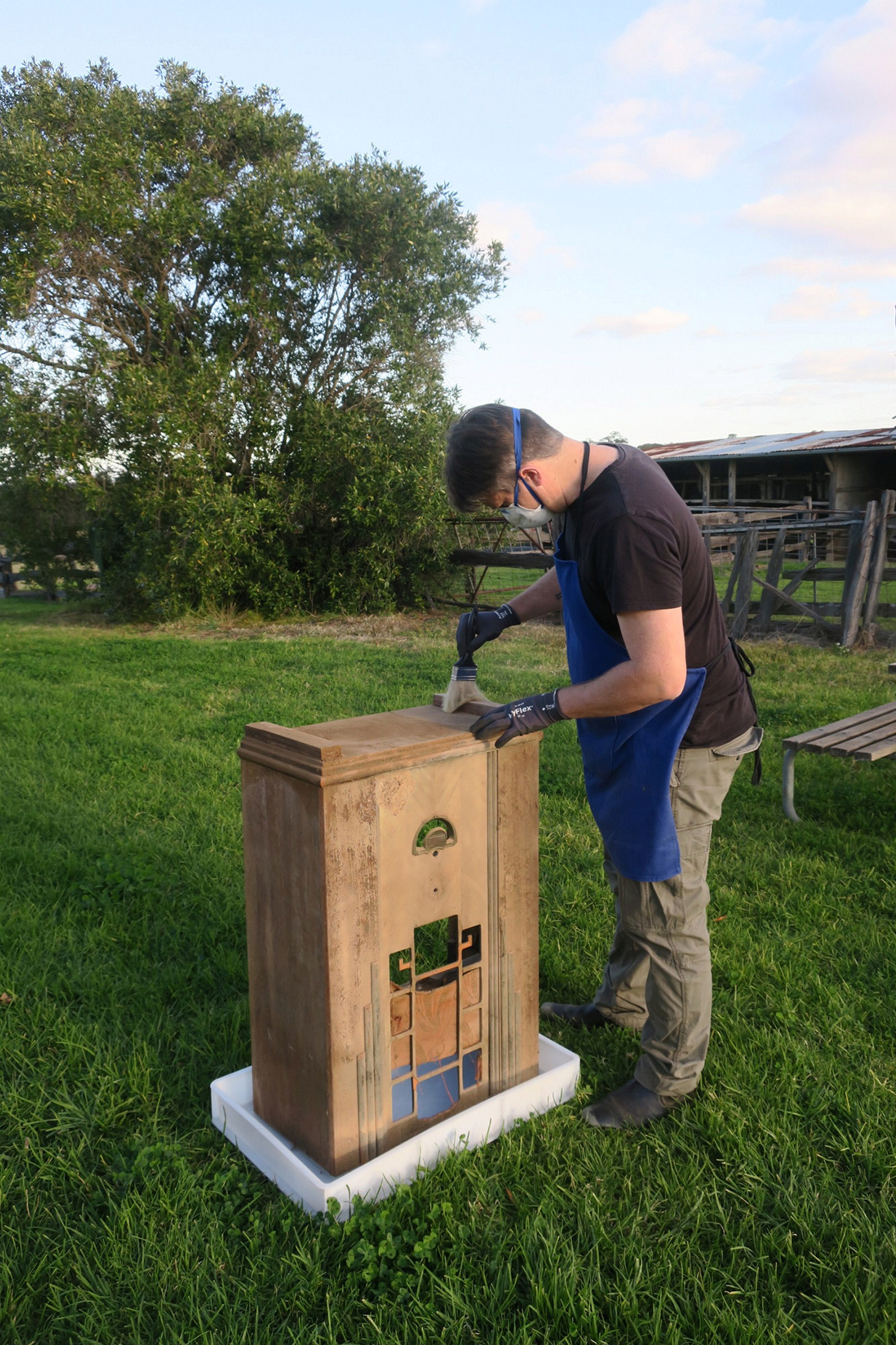 Outdoors shot of man cleaning wooden radio cabinet.