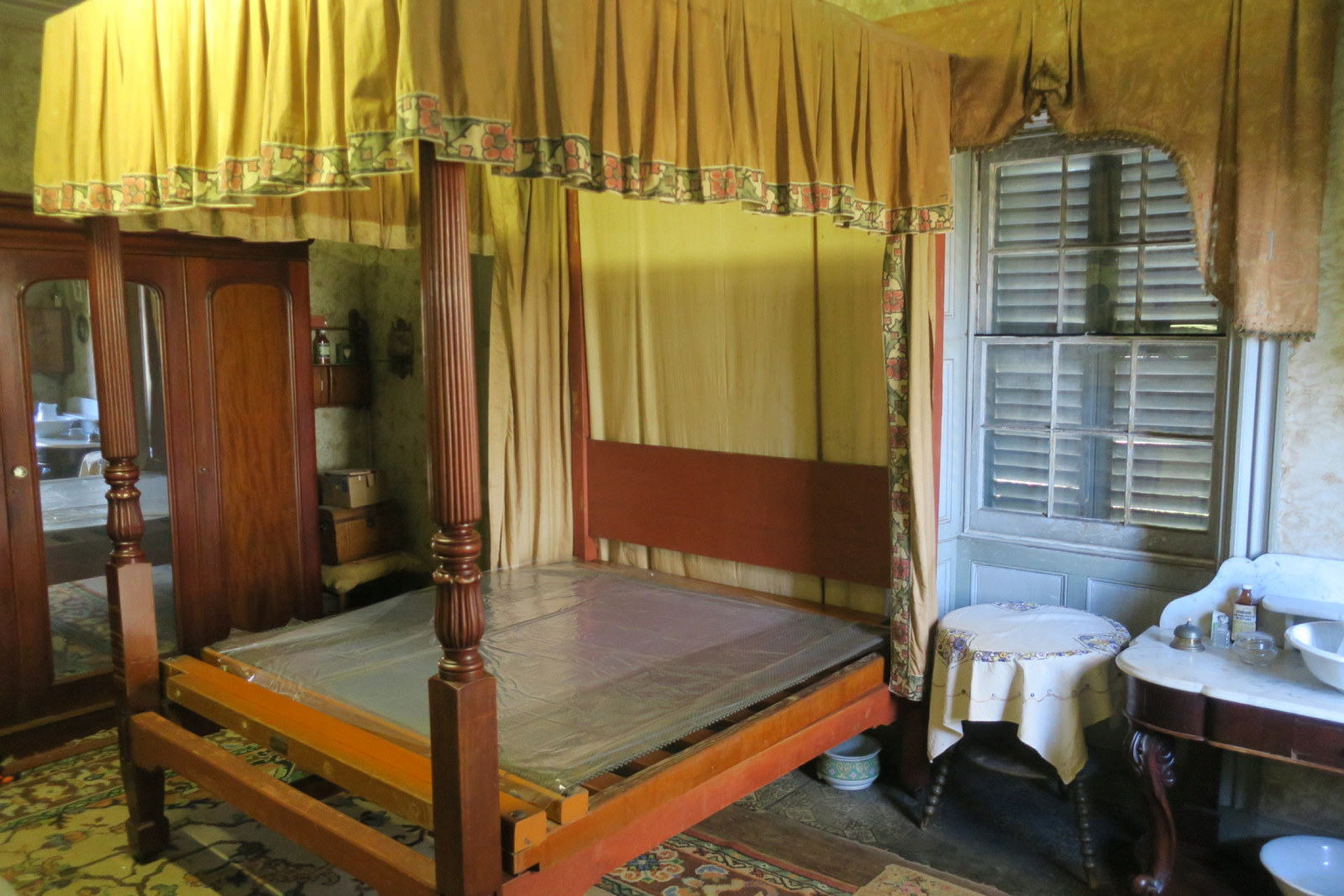 Interior view of bedroom, showing bedcovers being removed for cleaning.