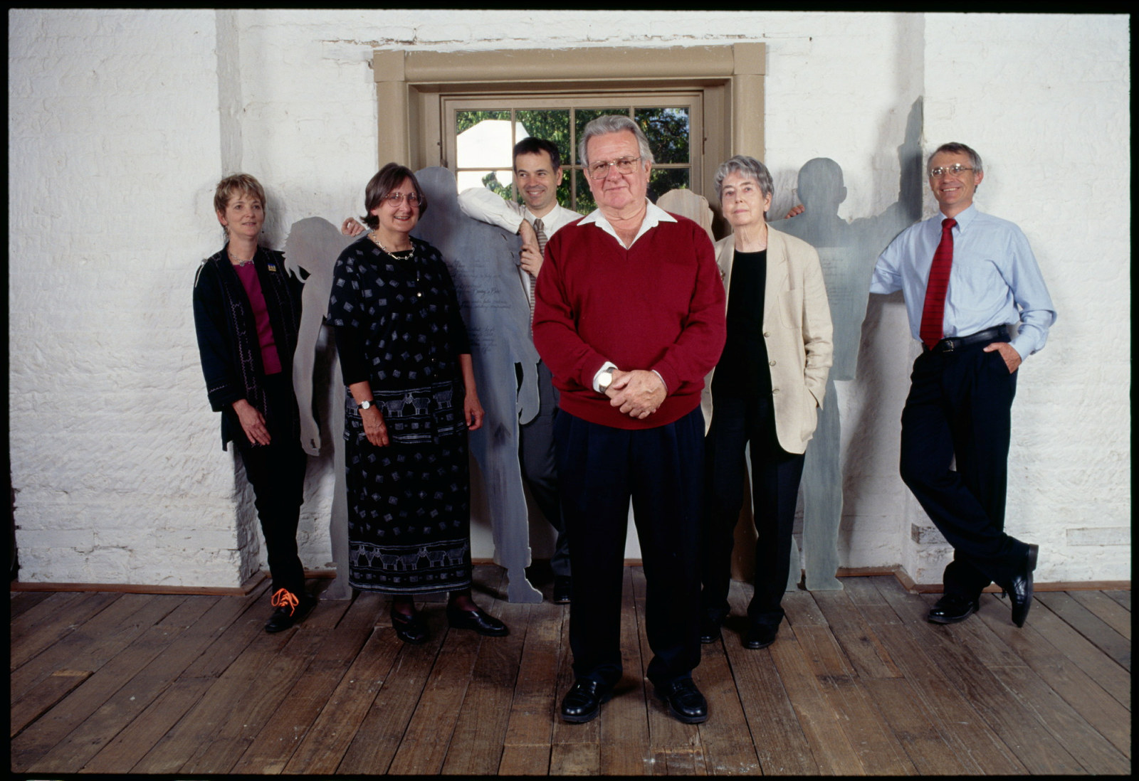 Group of people in white walled room with lifesize cutout figures behind.