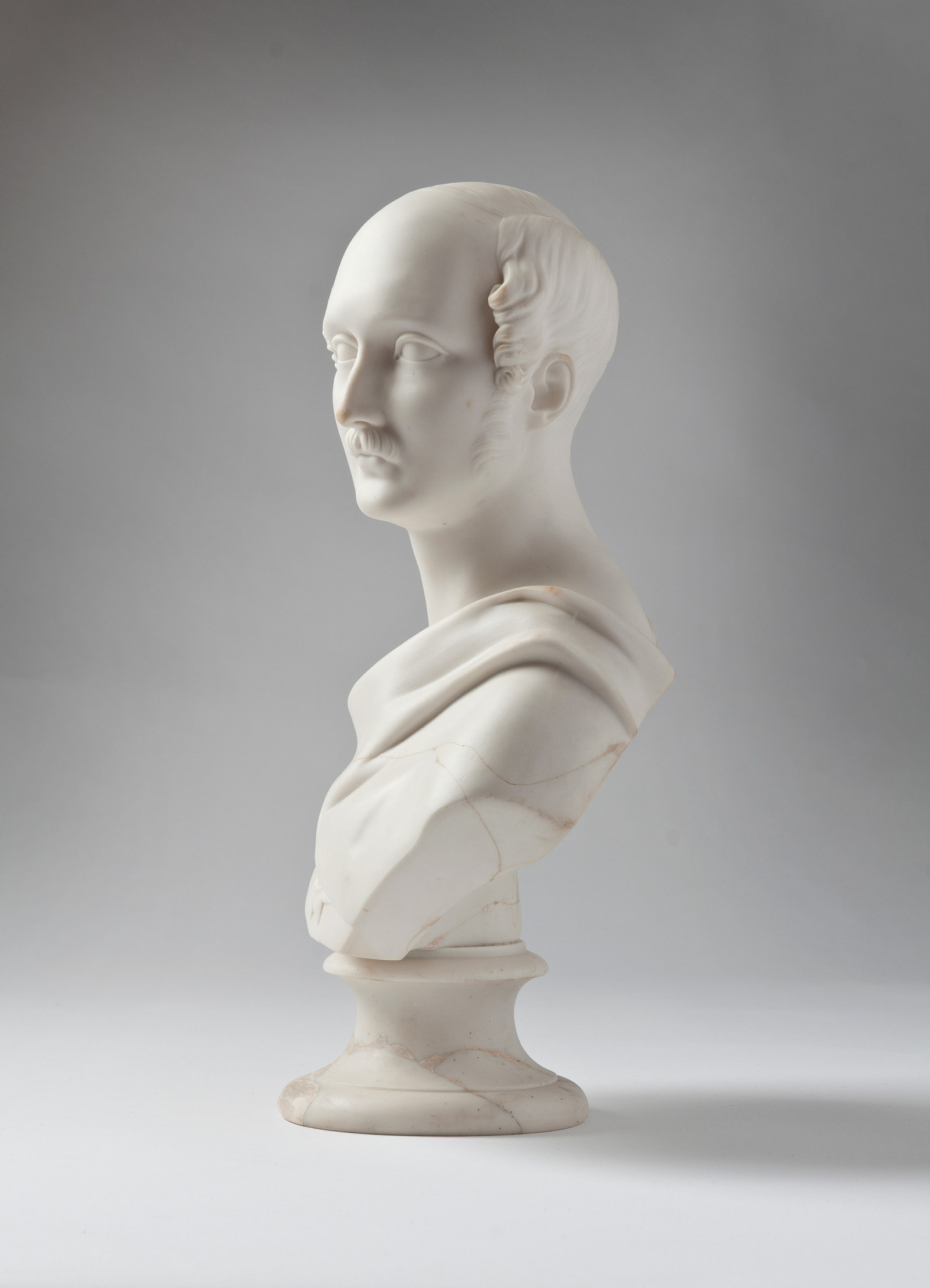 Bust of main in high 3/4 profile, with moustache and sideburns, robed.