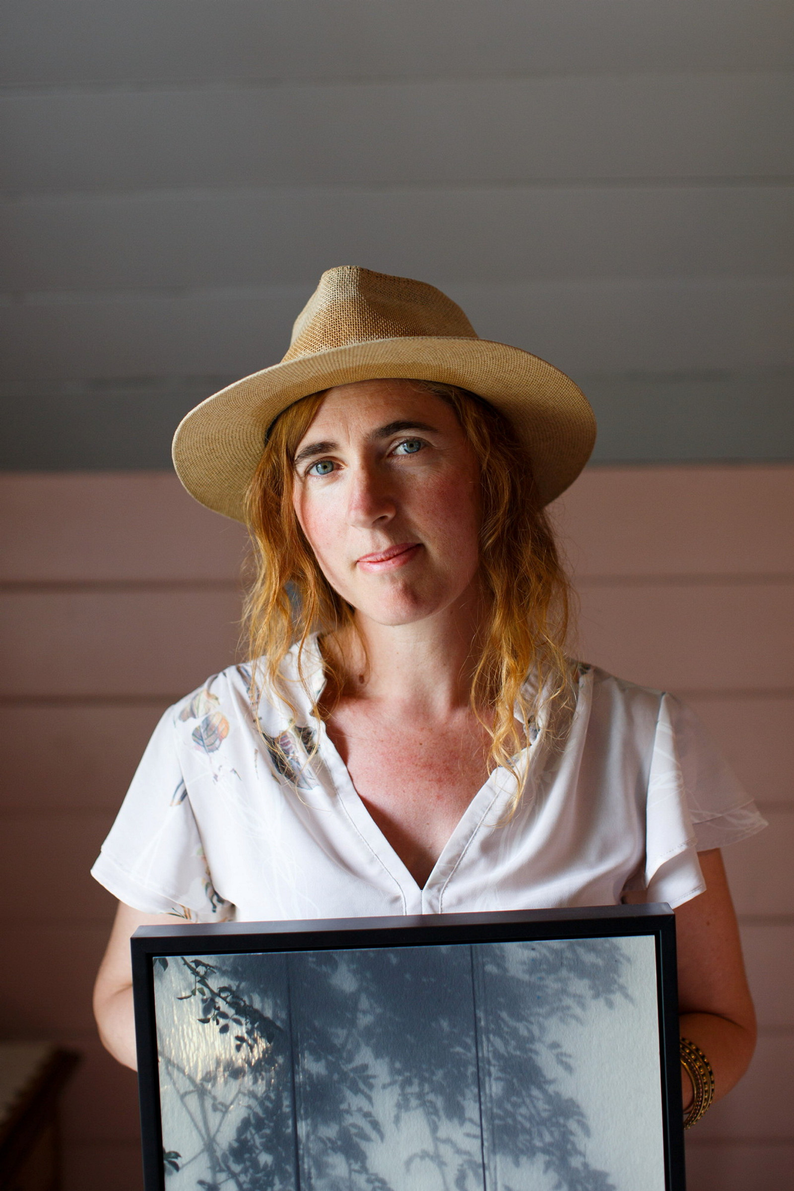 Women in straw hat and white shirt holding photographic artwork