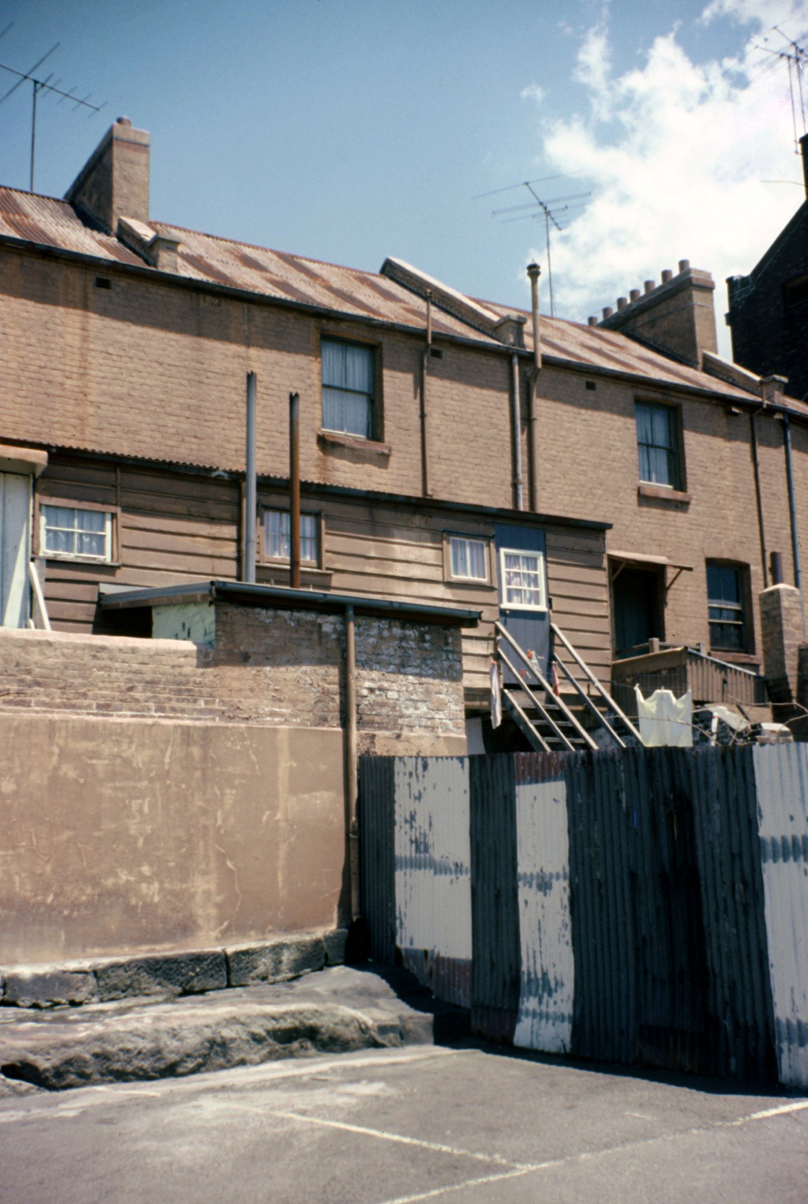Back view of row of terrace houses showing fences and yards.
