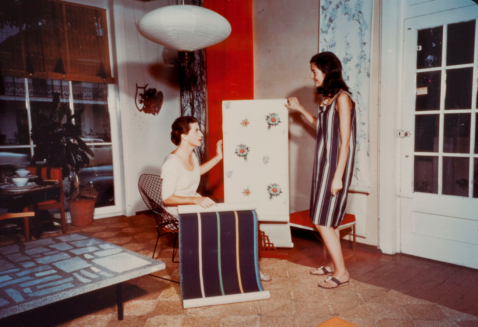 Photograph of two women in a store looking at wallpaper.