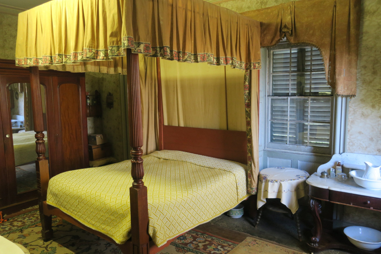 Interior view of bedroom, showing bedcovers being removed for cleaning.