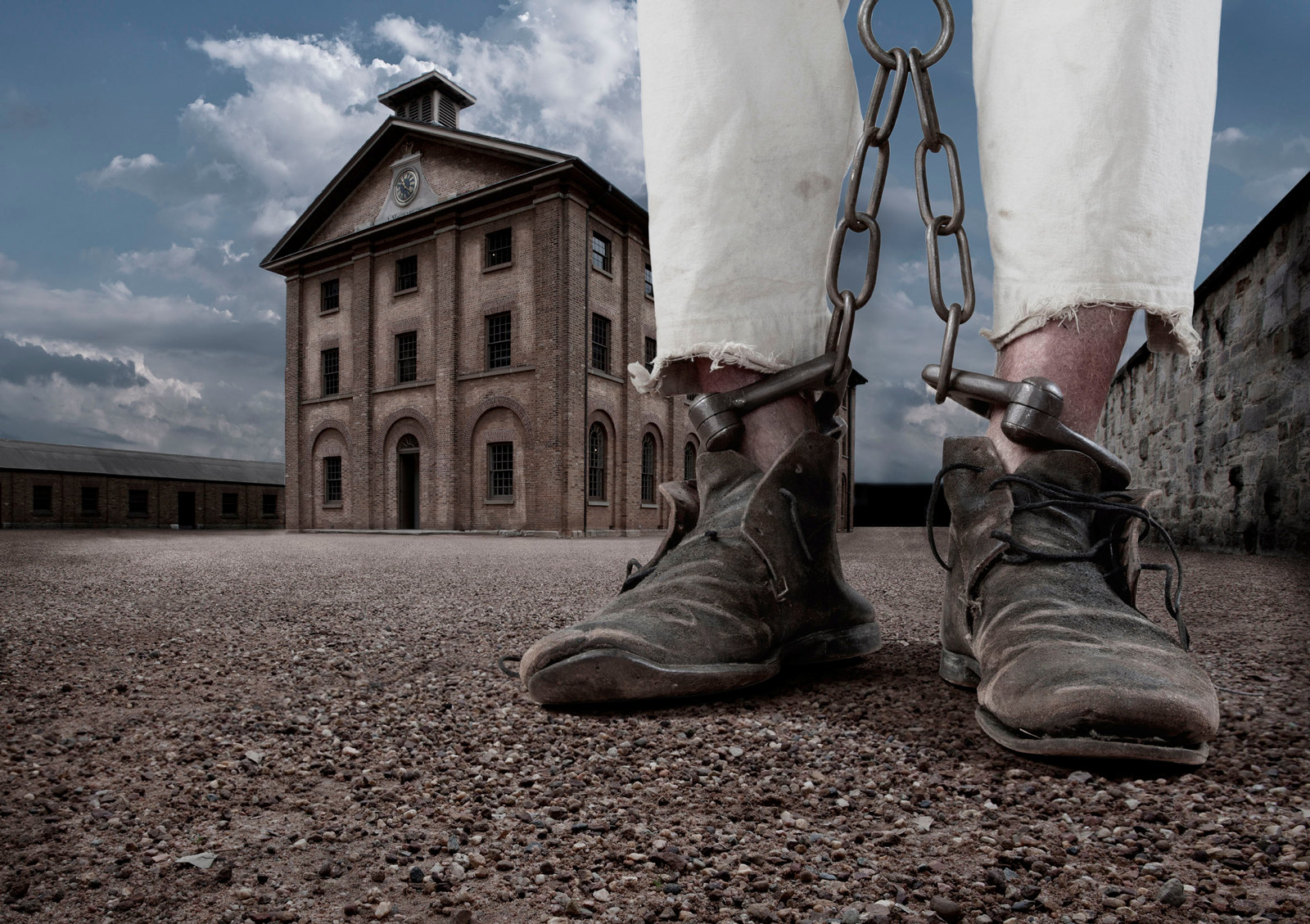 Image of chained legs (boots and white trousers visible) with Hyde Park Barracks in background.