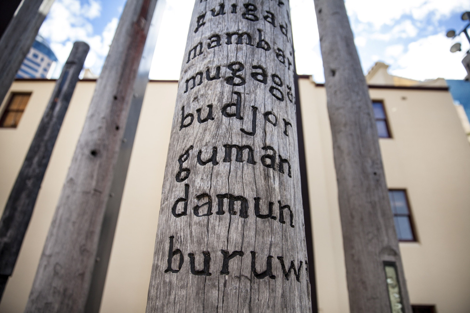 Wooden posts with carved words in indigenous languages.