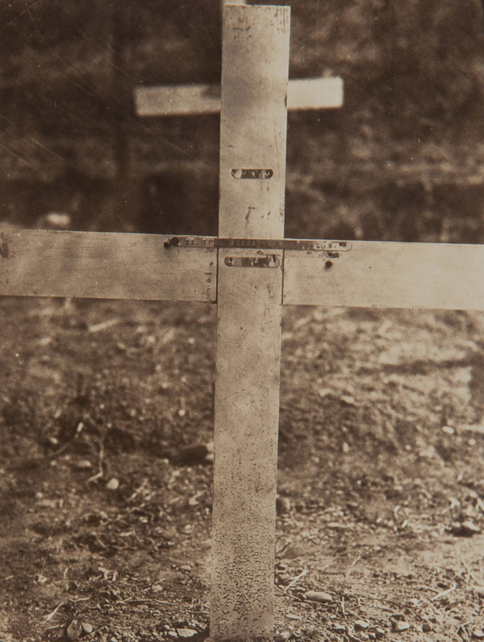 Cropped photograph to show detail of grave marker with metal strip attached.