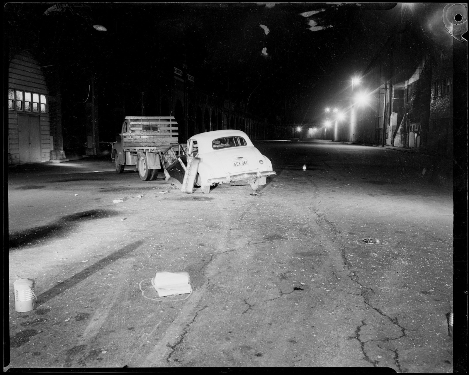 Night street scene showing damaged car collided with rear of utility truck with lanterns on road and book circled with chalk.