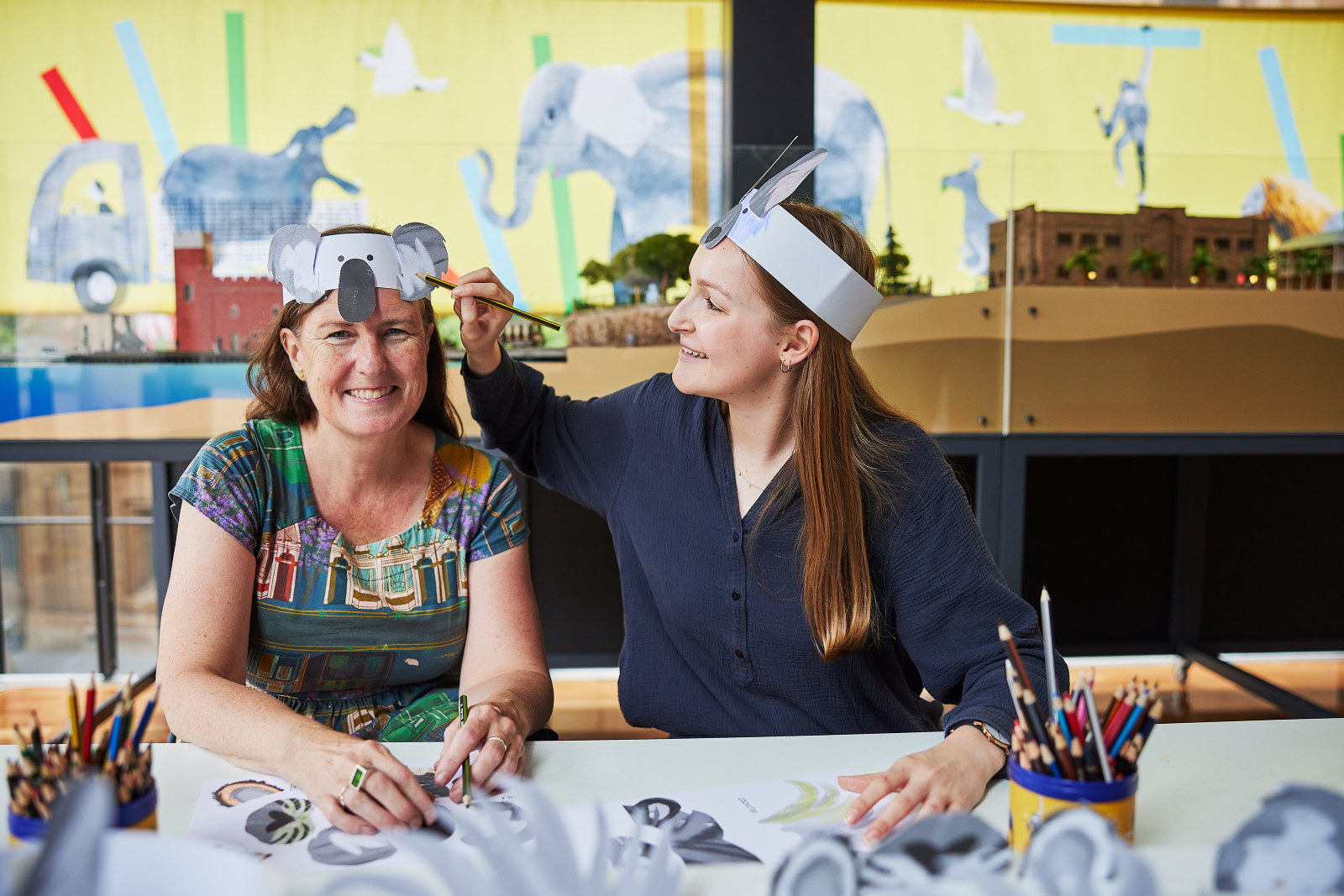 Lorinda Taylor, SLM Graphic Designer, and Mia Newton, Design Intern for How to Move a Zoo, colour in animal ears and noses in the 'Build your own animal' craft activity hub.