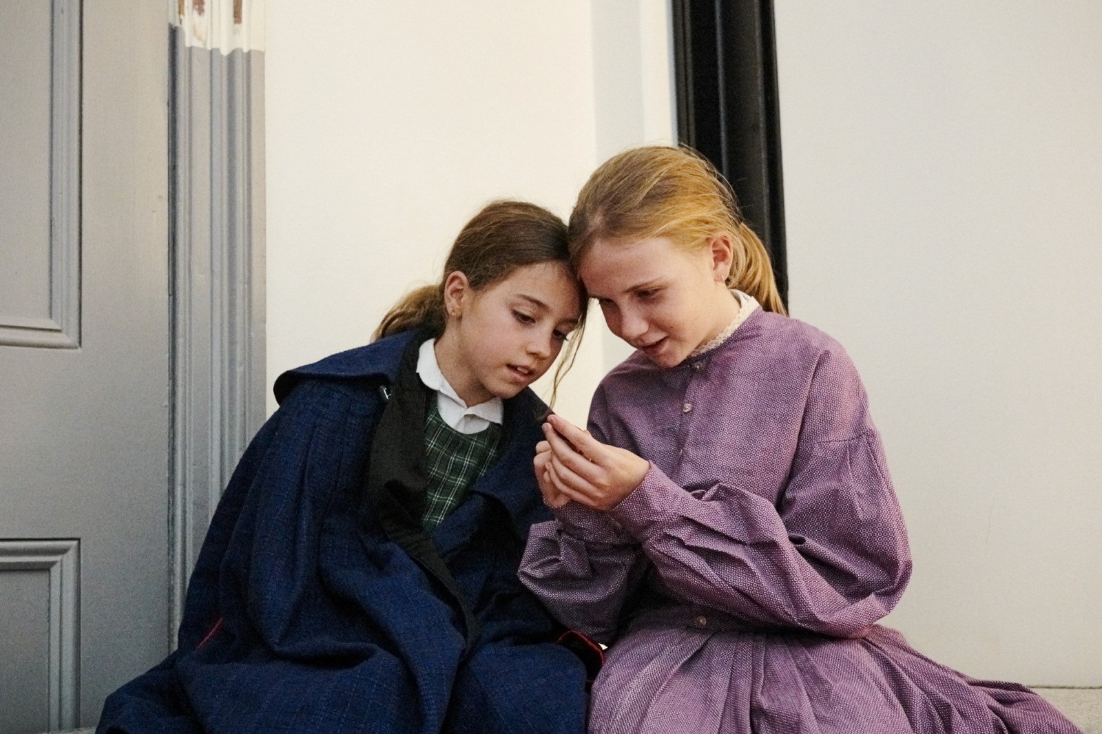 Two girls dressed in costume in large dormitory style room.