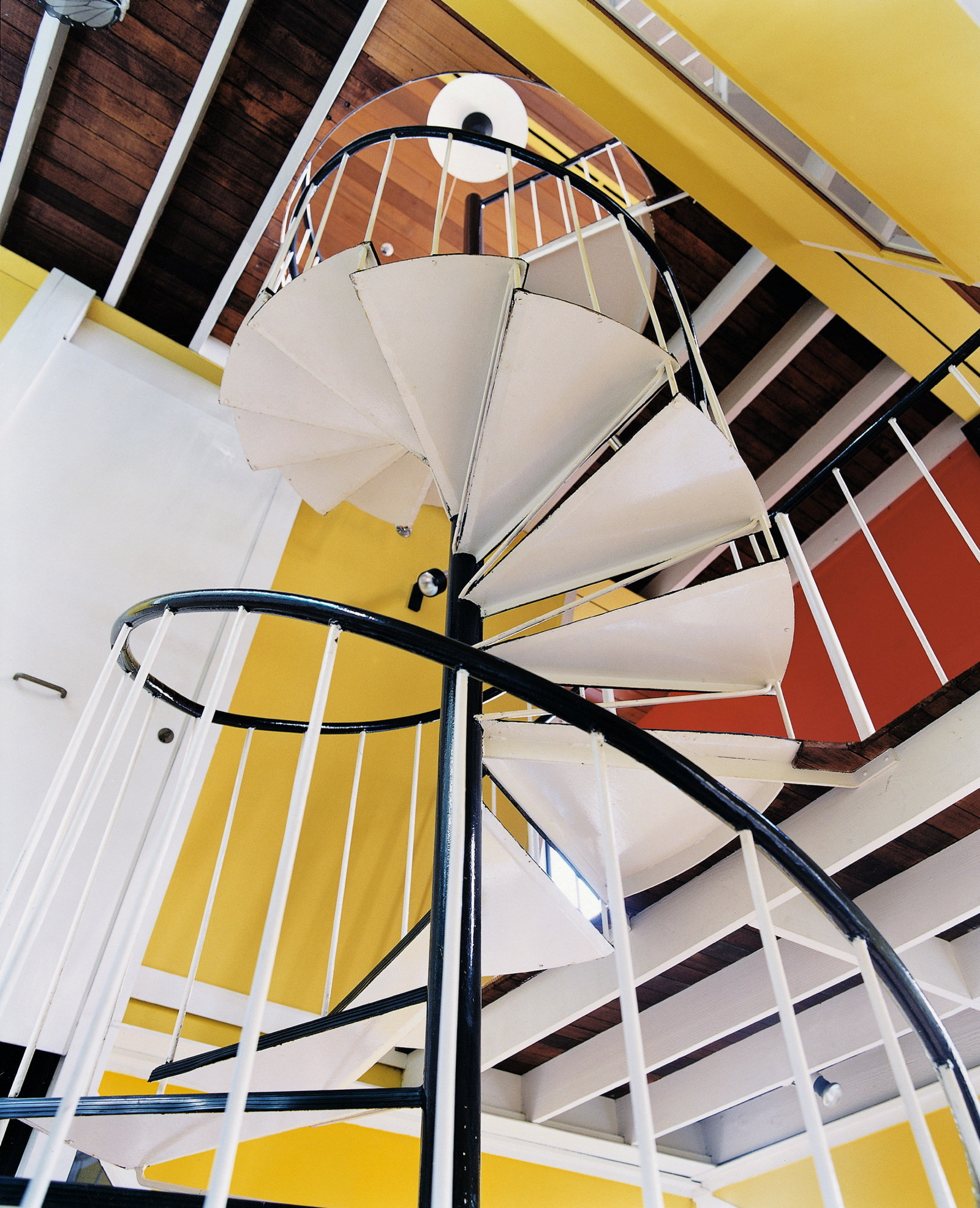 The interior spiral staircase and strong wall colours shown from below, the Butterfly House