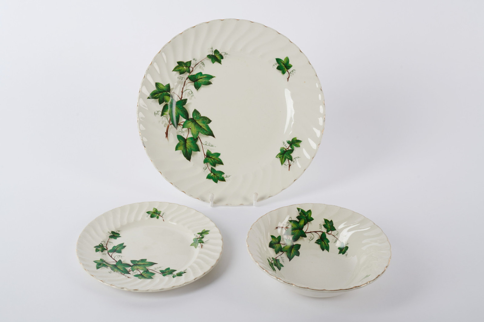Three pieces of white crockery with green leaf design.