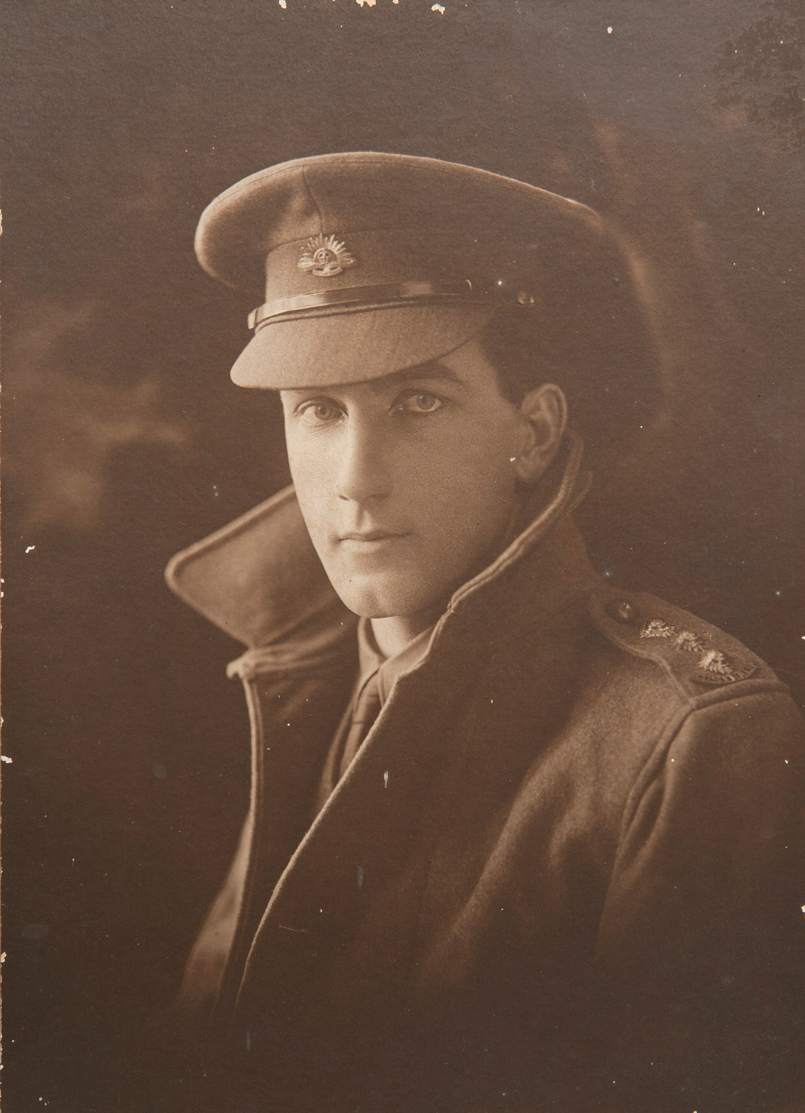 Photo of man in army uniform with coat collar turned up and cap.