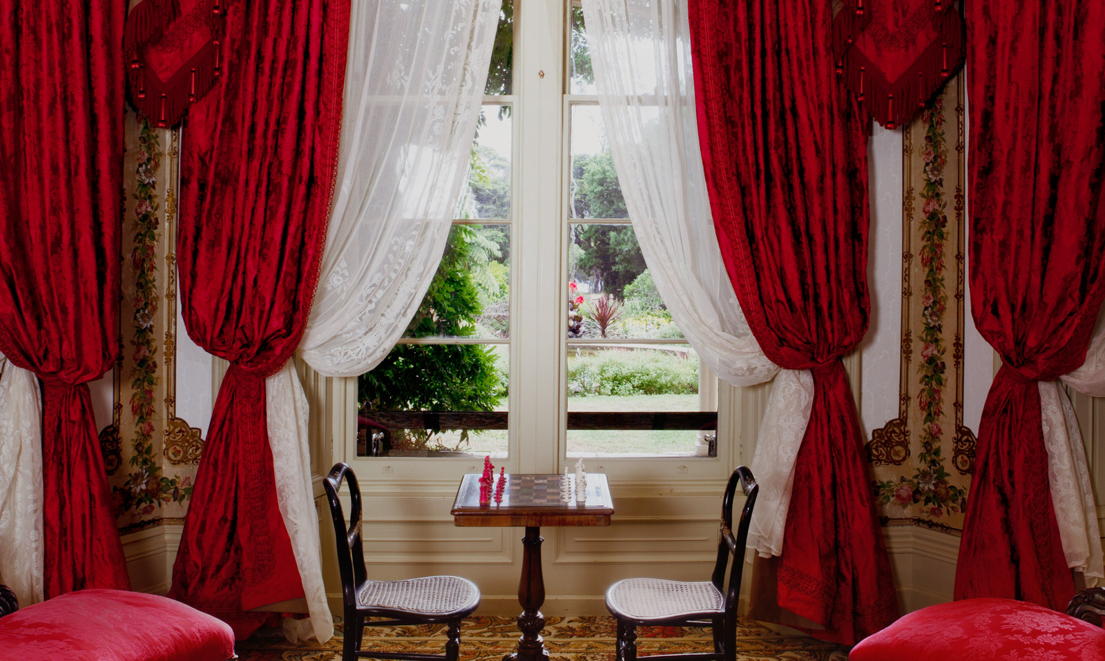 Lavishly draped windows behind drawing room furniture.