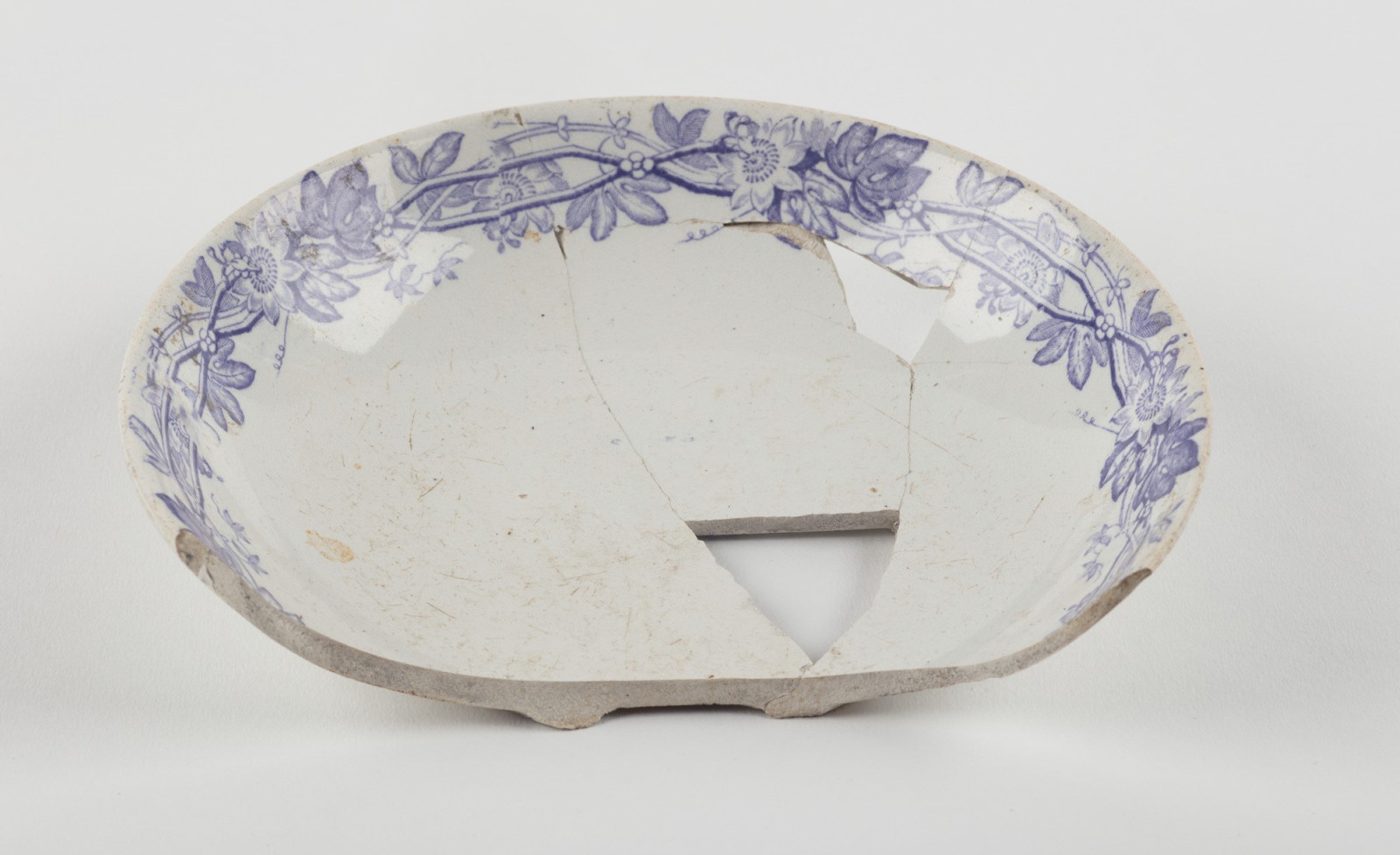 Ceramic saucer fragment with purple passion flower transfer print around internal rim