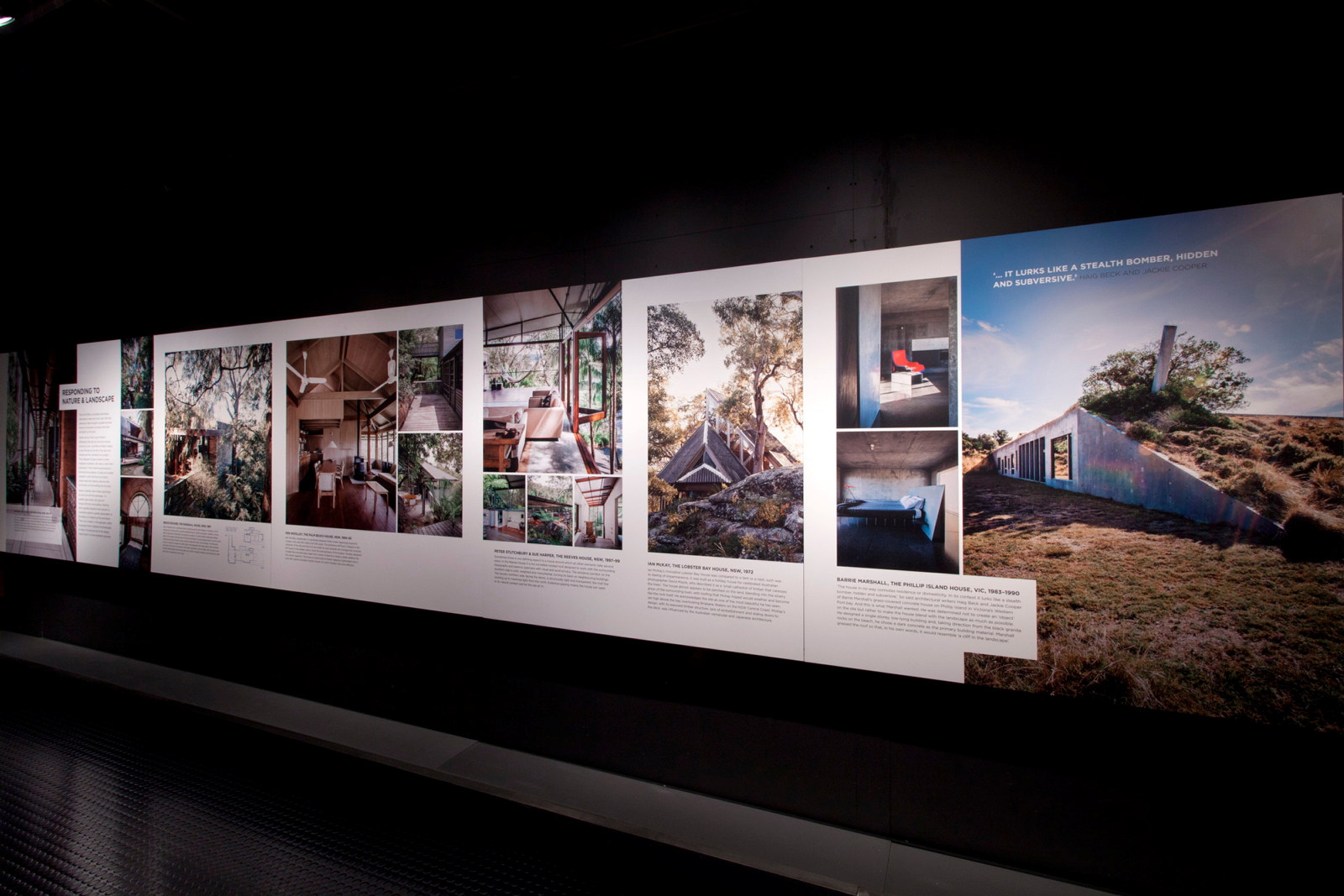 This is a photograph of a strip of exhibition panels with a series of colour photographs along a black wall