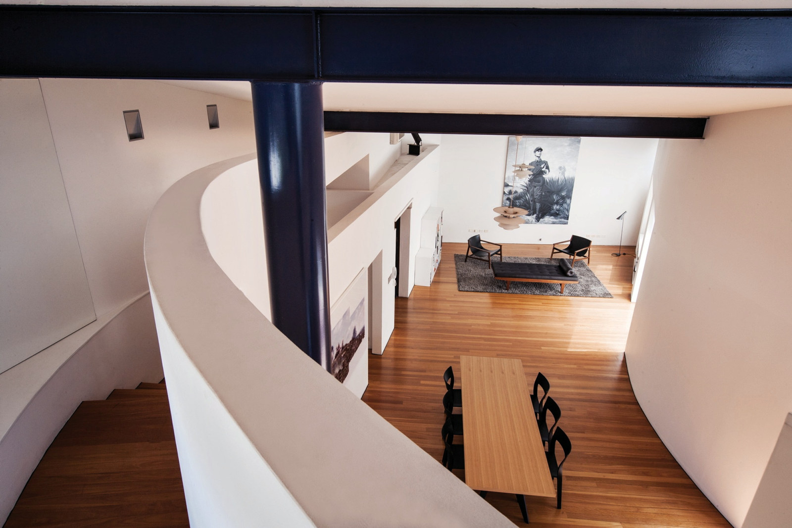 Interior photograph from the mezzanine of the Droga Apartment showing a sweeping wall and staircase