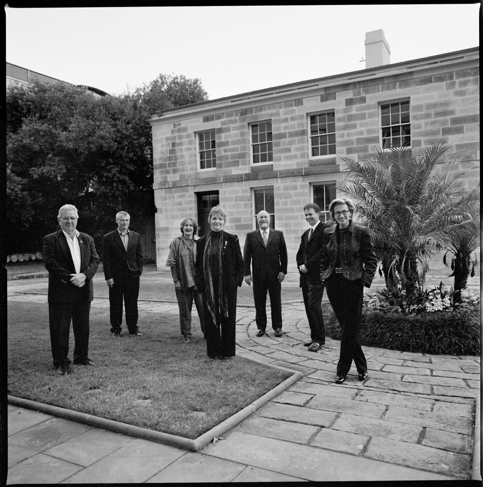 Black and white photo of group in sandstone courtyard.