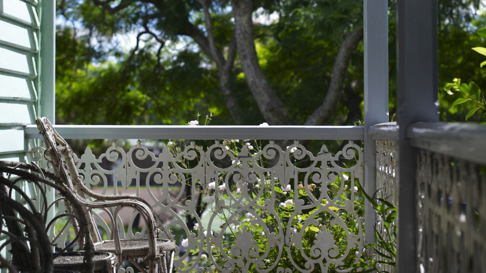 Detail of ironwork and cane chairs on sunny verandah.