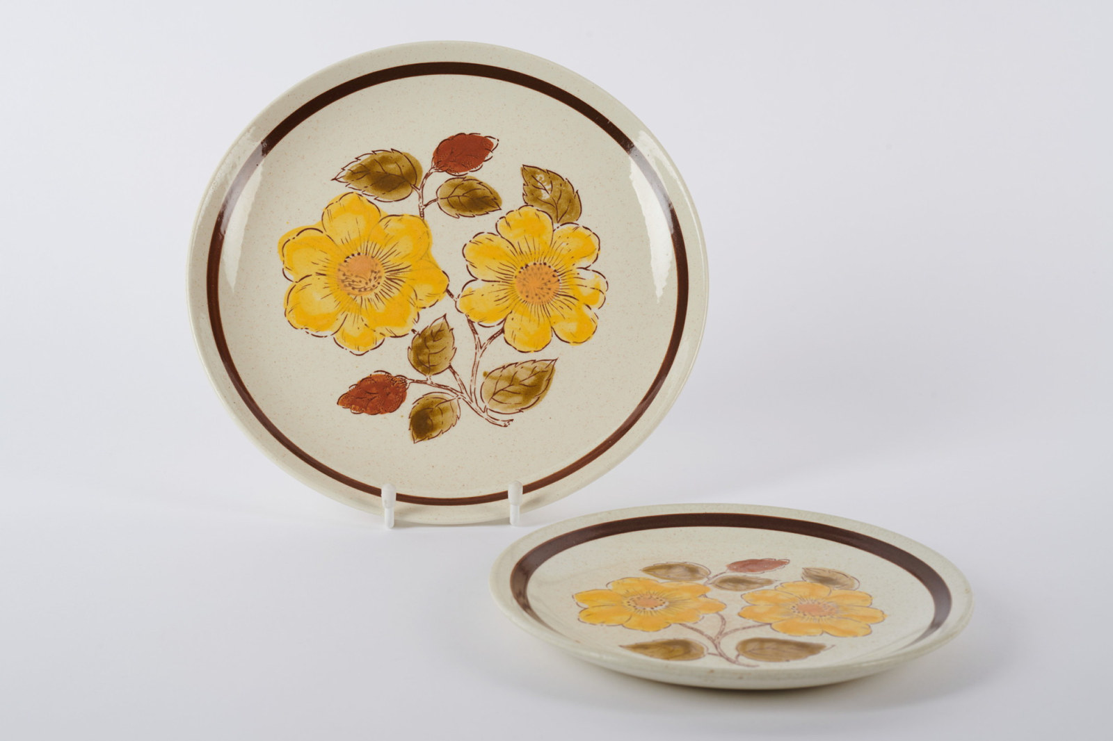 Two plates with yellow flower pattern and brown border.