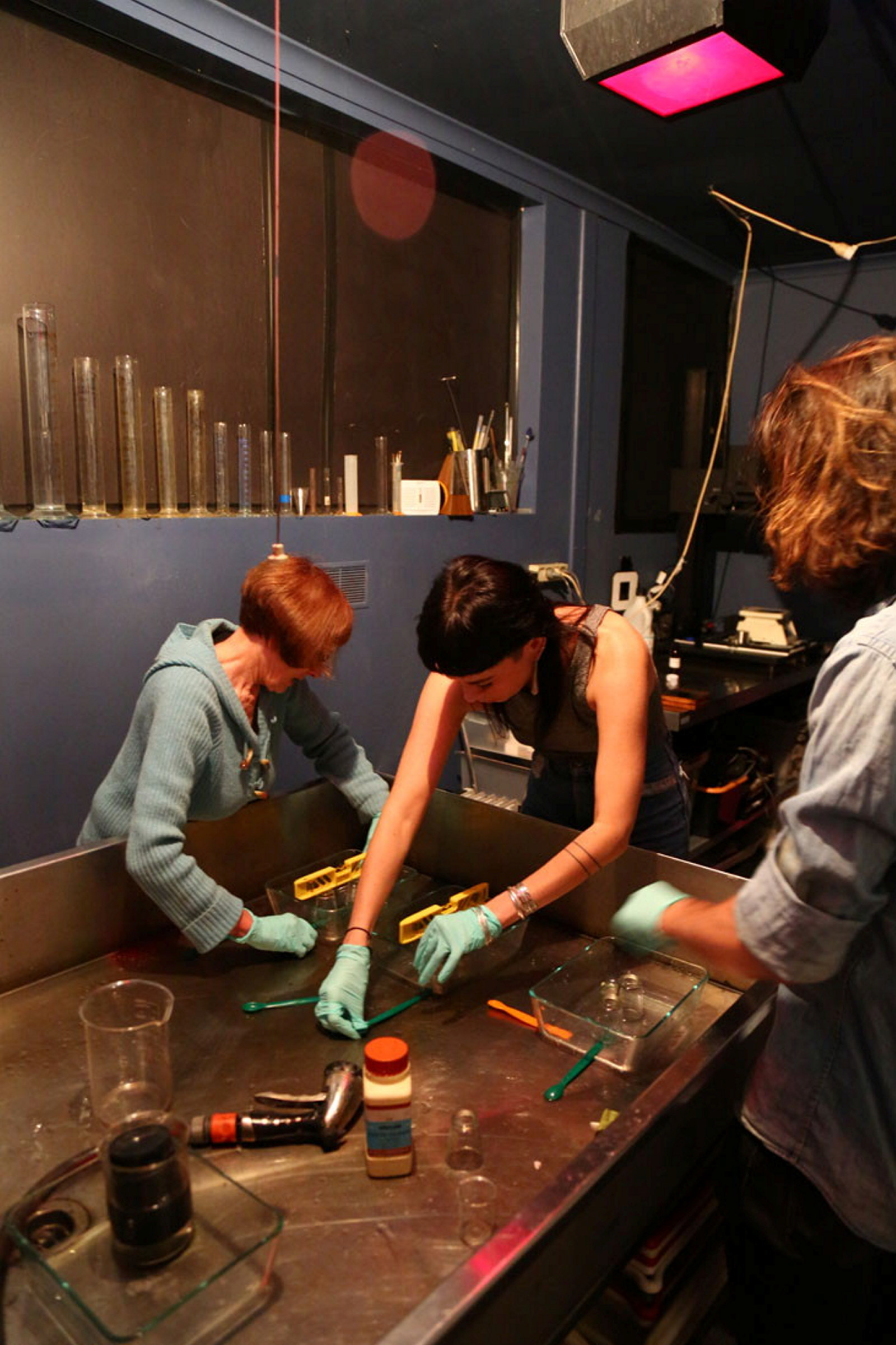 Group of people working with glass plates at wooden bench.