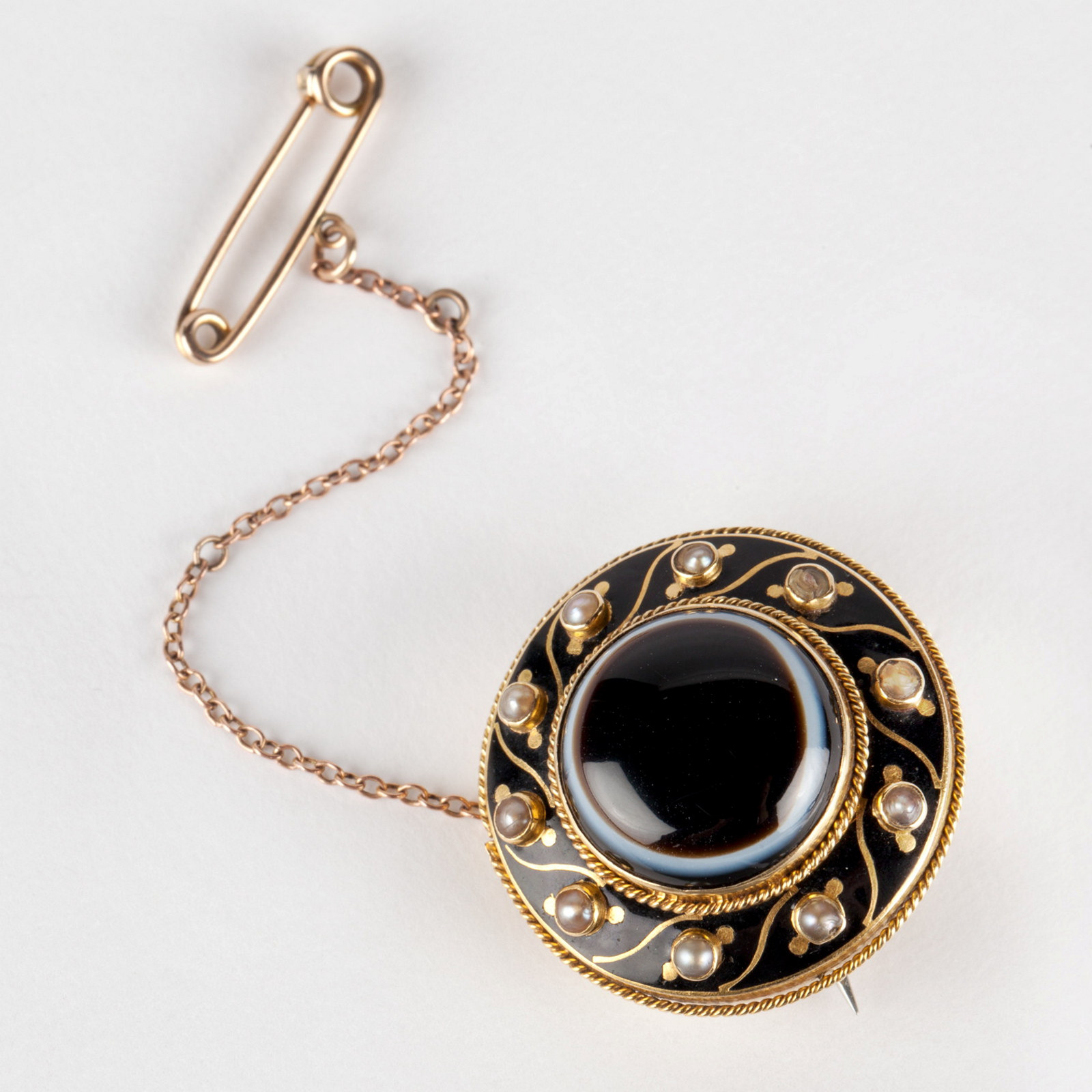 Gold and black round enamel brooch set with dark banded onyx and seed pearls, circa 1870