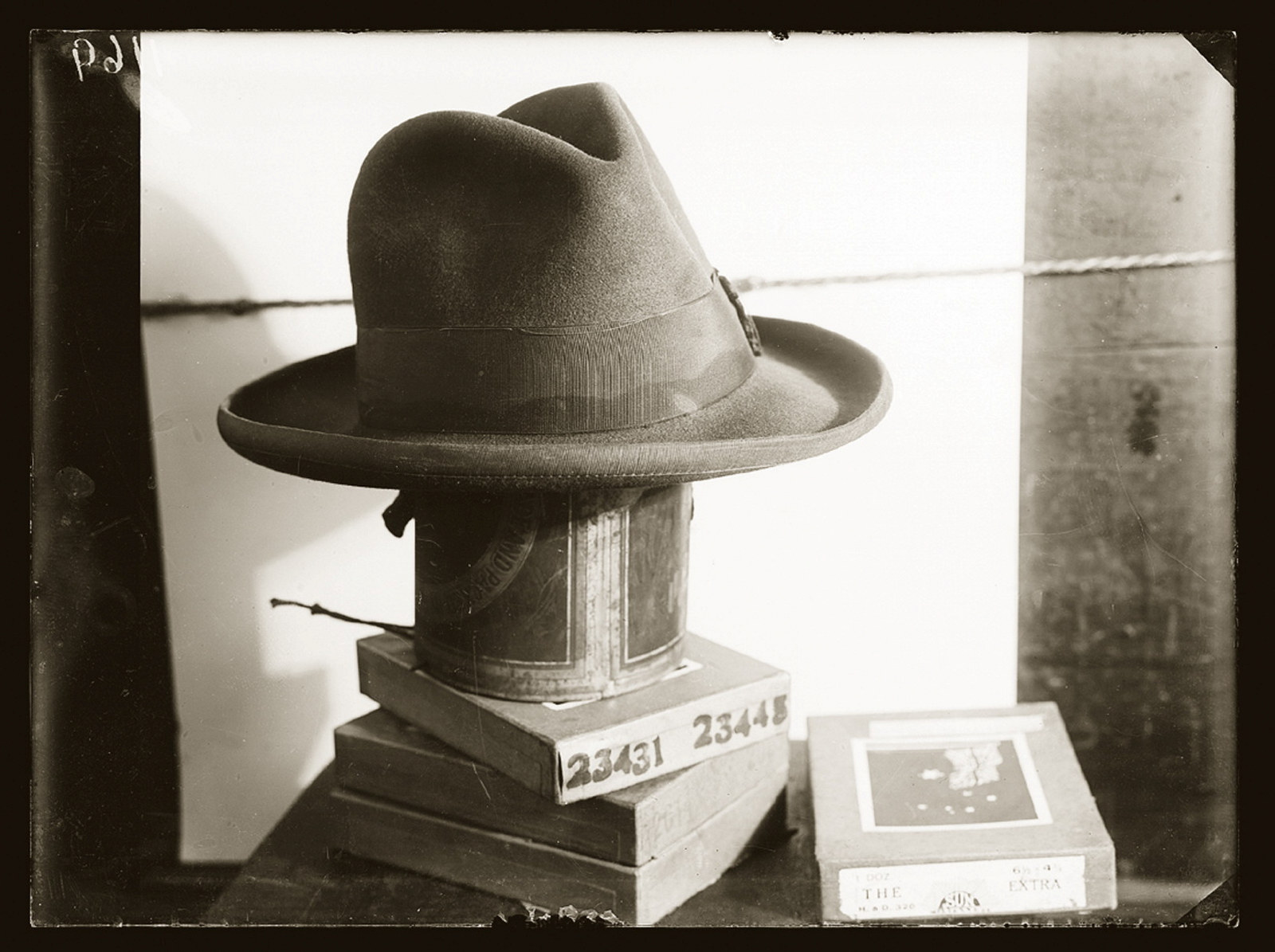 Man's sweat-stained Fedora hat, presumably evidence in a criminal matter, atop boxes of police negatives. Location and details unknown, but possibly CIB, Sydney, ca.1928.
