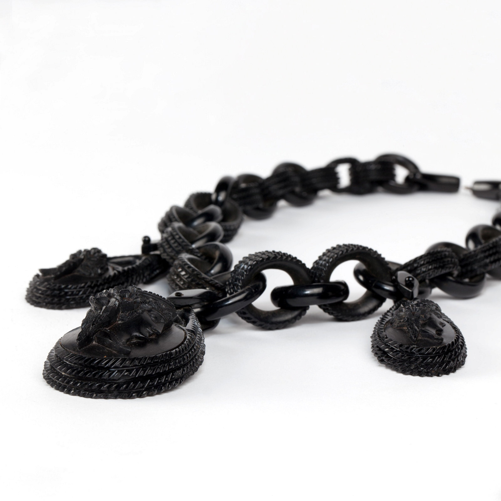 Detail view of pendants on a vulcanite necklace. The necklace is composed of 32 graduating oval links and three oval pendants.