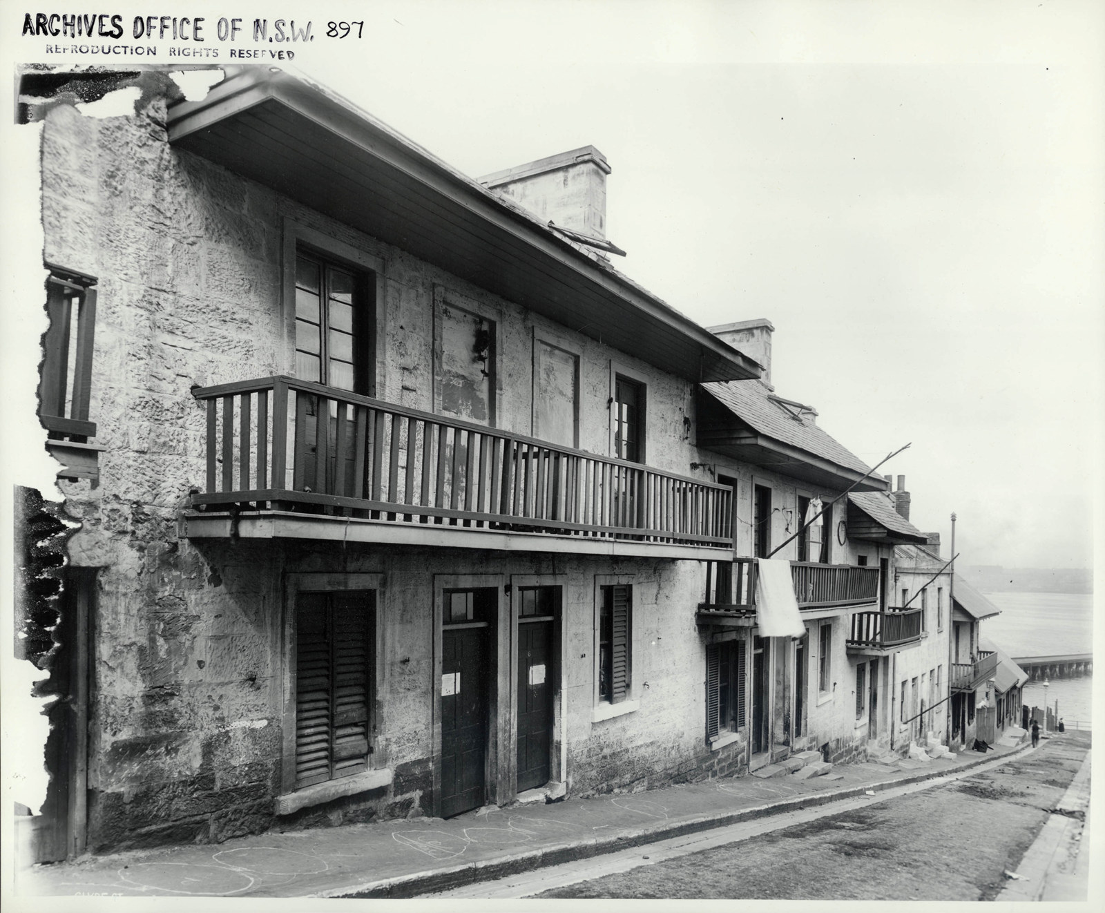 Photograph of row of terrace houses lining a street that slopes down to the edge of the harbour.