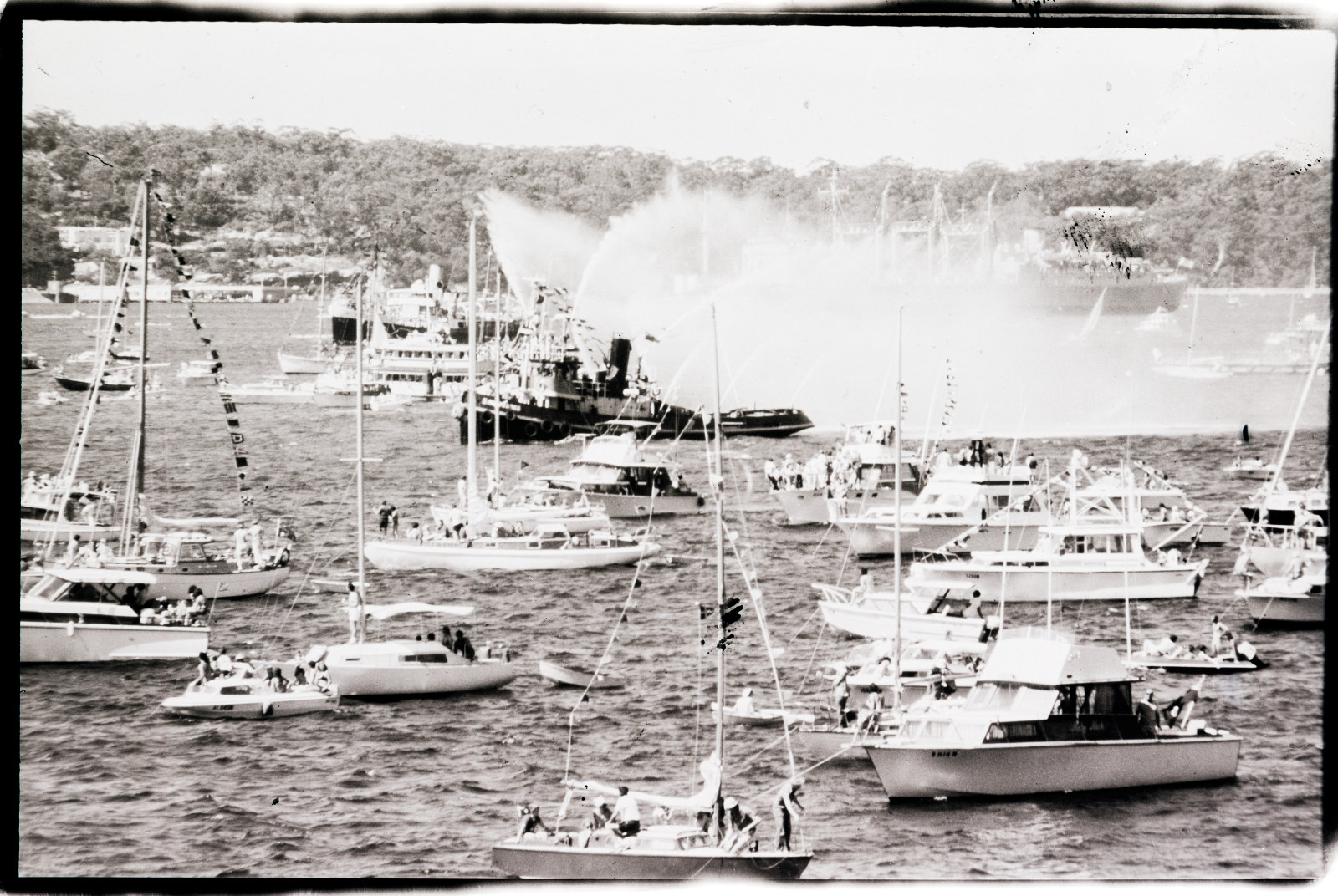 Fireboat spraying water jets and a flotilla of pleasure craft on the harbour during the opening festivities for the Sydney Opera House, 20th October 1973.